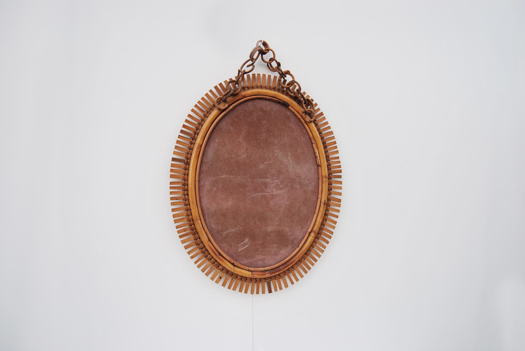 Miroir ovale en bambou, fabriqué en Italie, années 1960. 
Élégant miroir mural ovale avec chaîne en rotin. Conservant la patine du temps, son état est excellent. 
Le prix de l'expédition est pour le territoire italien, pour les îles et pour