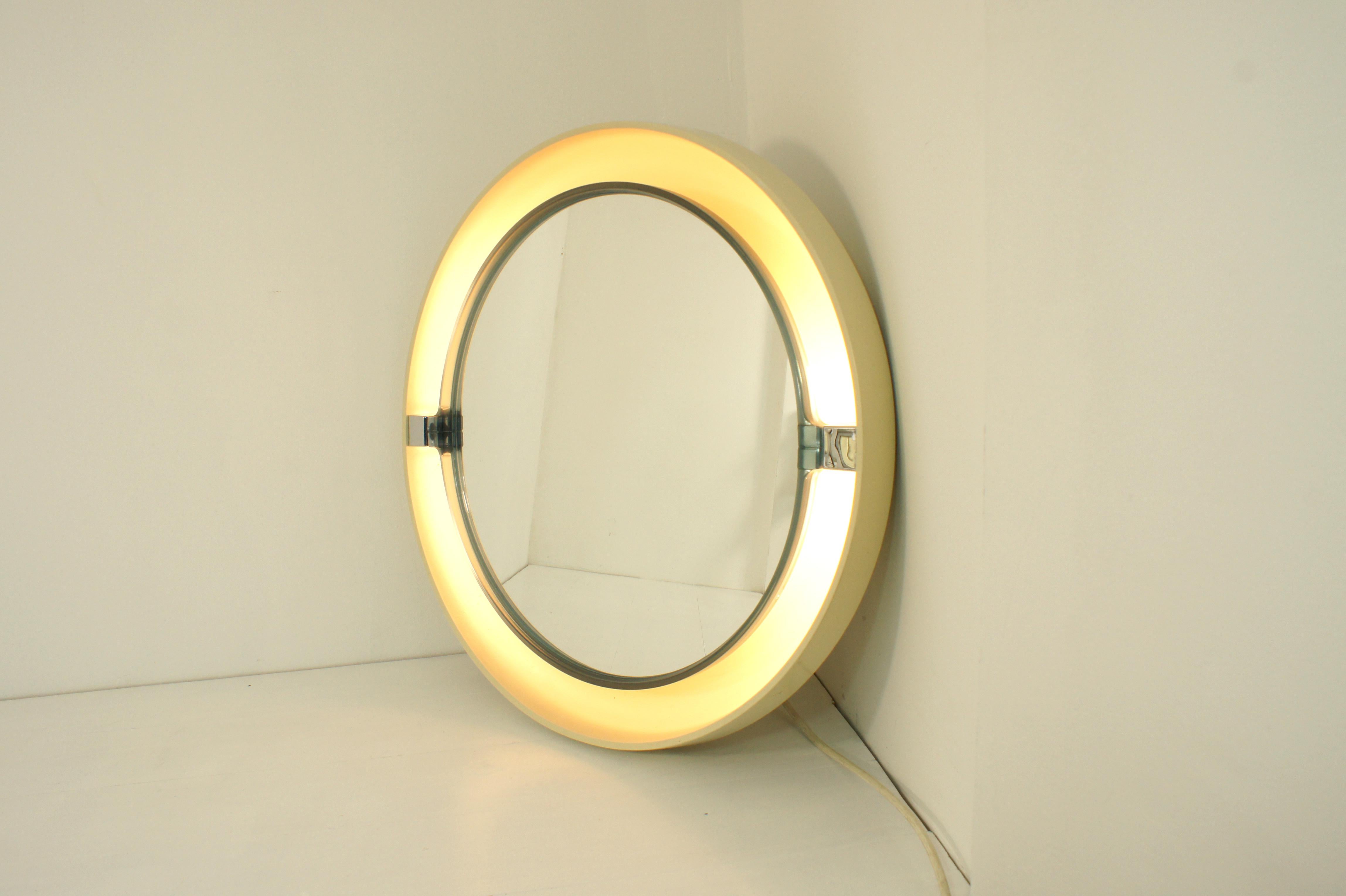 Miroir basculant et rétro-éclairé fabriqué dans les années 1970 par Allibert, Allemagne.

Coque en abs blanc sur laquelle est monté un cadre basculant bleu semi-transparent dans lequel est inclus le miroir.

Quatre ampoules E14 sont placées entre le