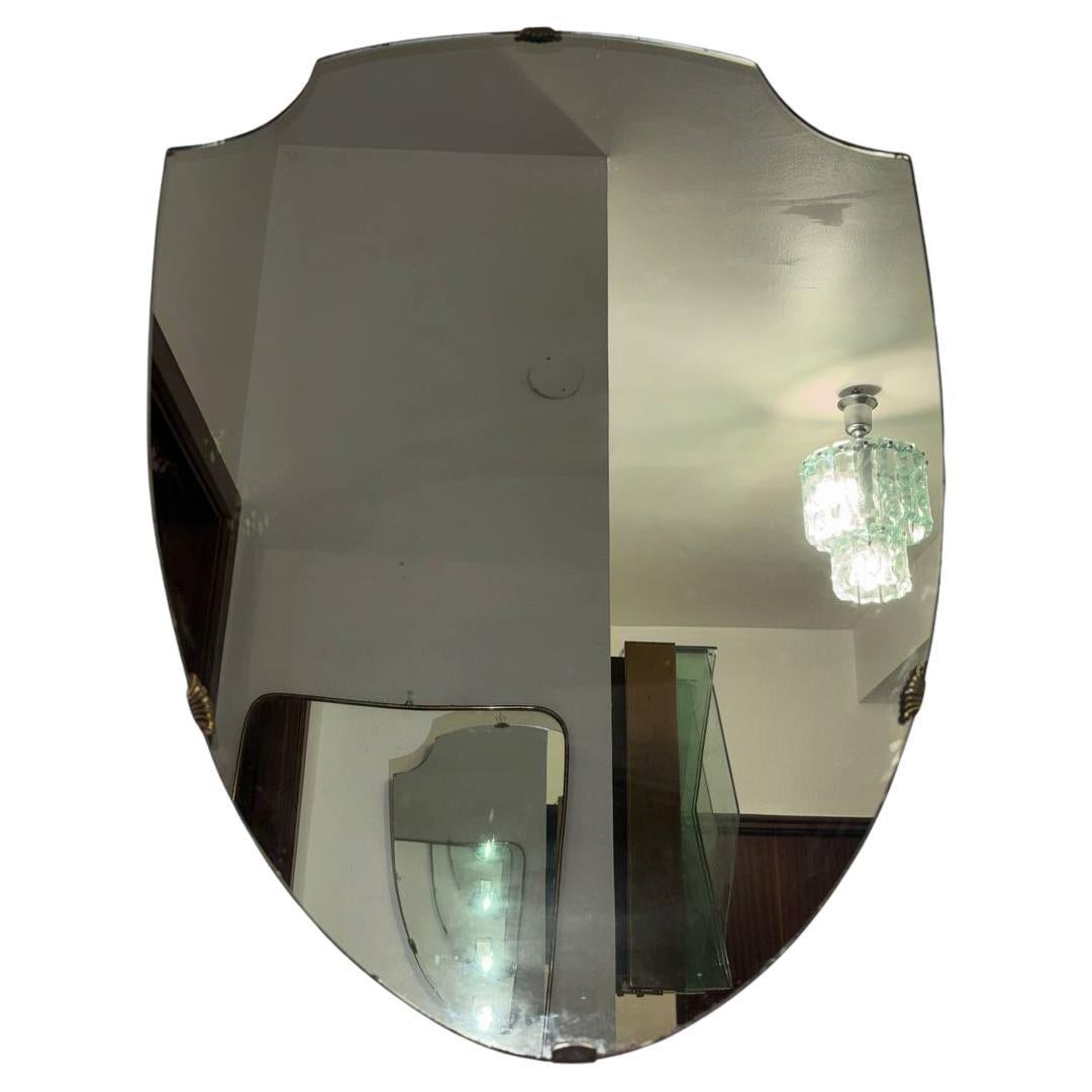 Ce miroir incarne l'élégance et l'esprit novateur du design italien des années 1950, en s'inspirant clairement de l'œuvre emblématique de Gio Ponti. Sa forme distinctive, qui ressemble vaguement à un bouclier avec un sommet ondulé, reflète une