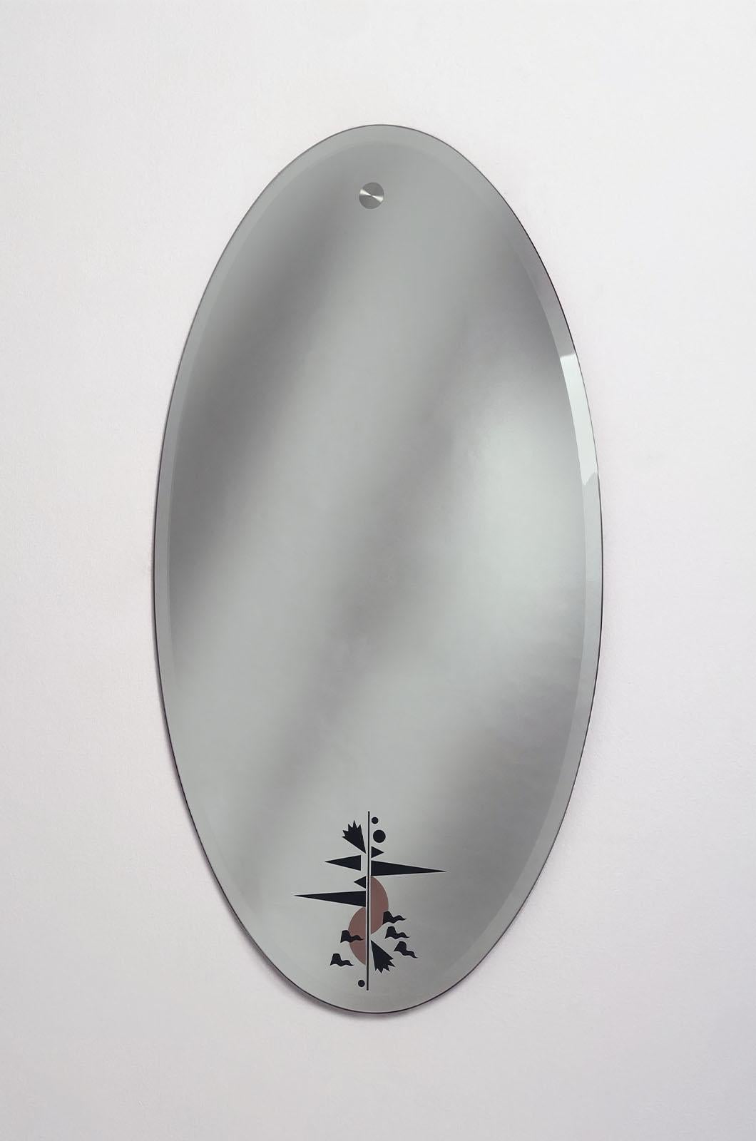 Miroir mural ovale conçu par Alessandro Mendini pour Zanotta en 1991. Le miroir se caractérise par une forme périmétrique simple avec un contour au sol.
L'élément d'accrochage au dos sert également de détail décoratif sur la partie supérieure de la