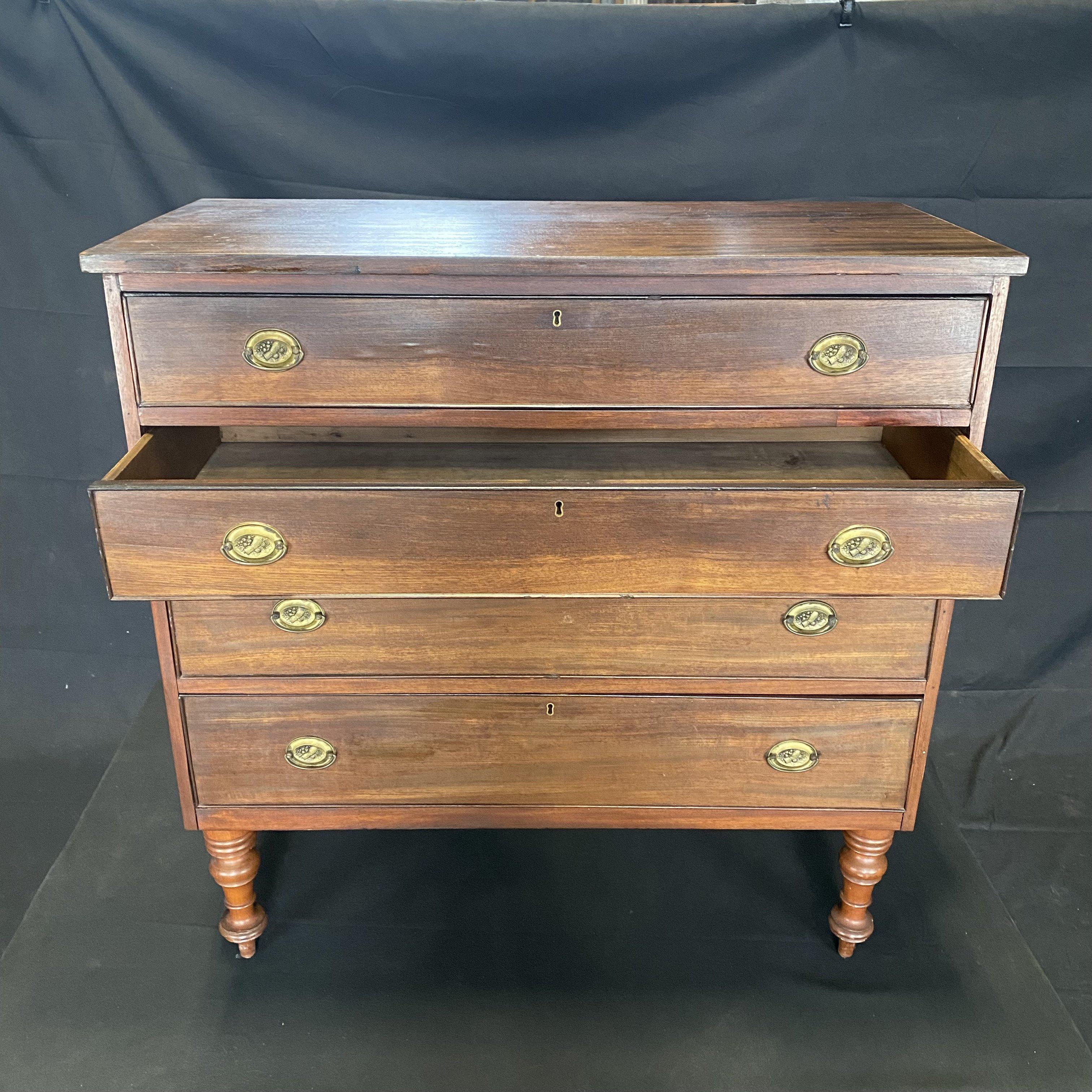 American Sheraton mahogany chest with four cock beaded drawers with original wheat sheaf, fruit and oval floral brasses and bail handles under the single board mahogany top. Classic simplicity of this early Colonial American dresser is complemented