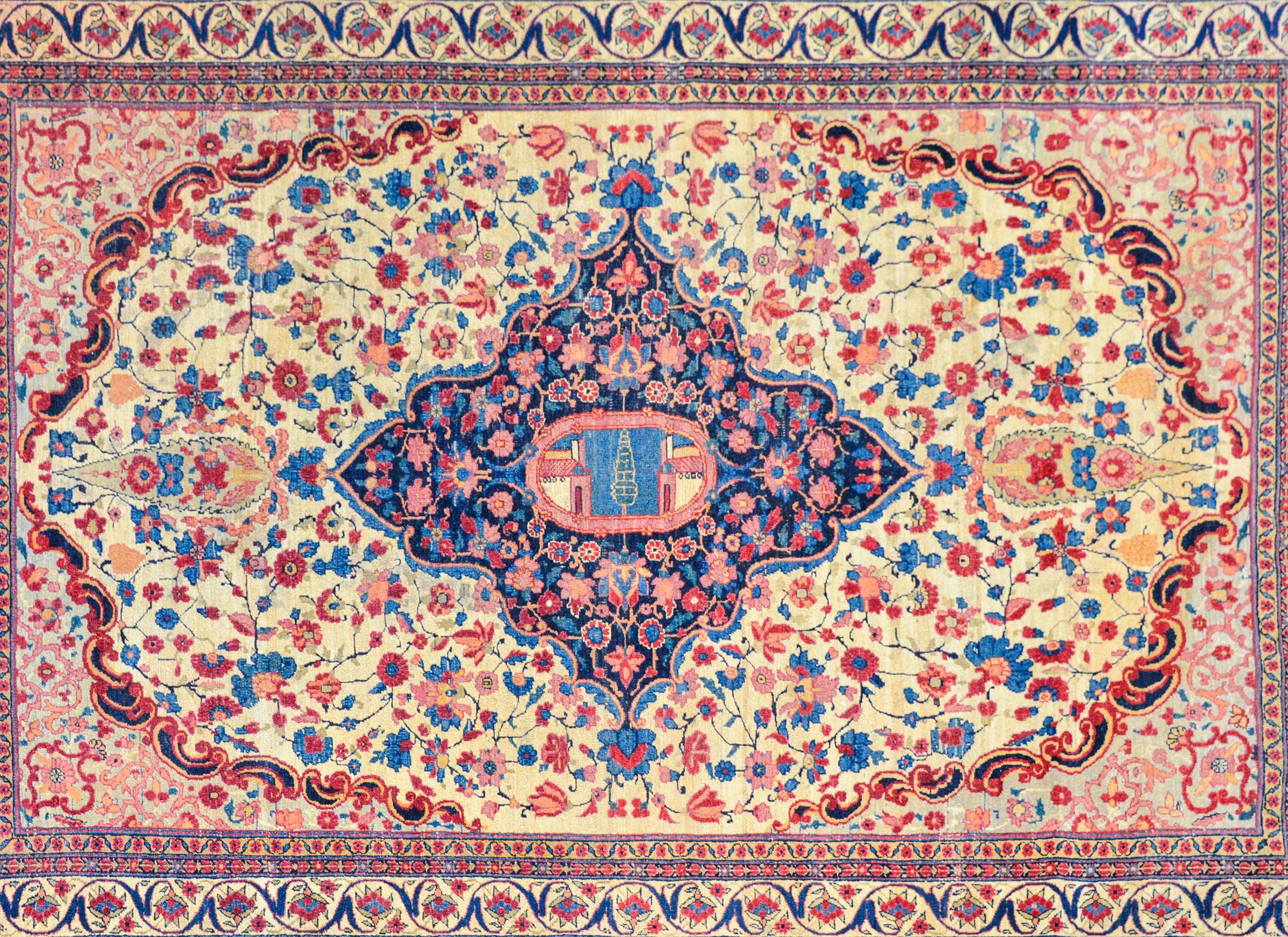 A special early 20th century Persian Tabriz rug with a central medallion woven with flowers and scrolling vines against a dark indigo background and a central image depicting two buildings flanking a central cypress tree. The medallion lives amidst