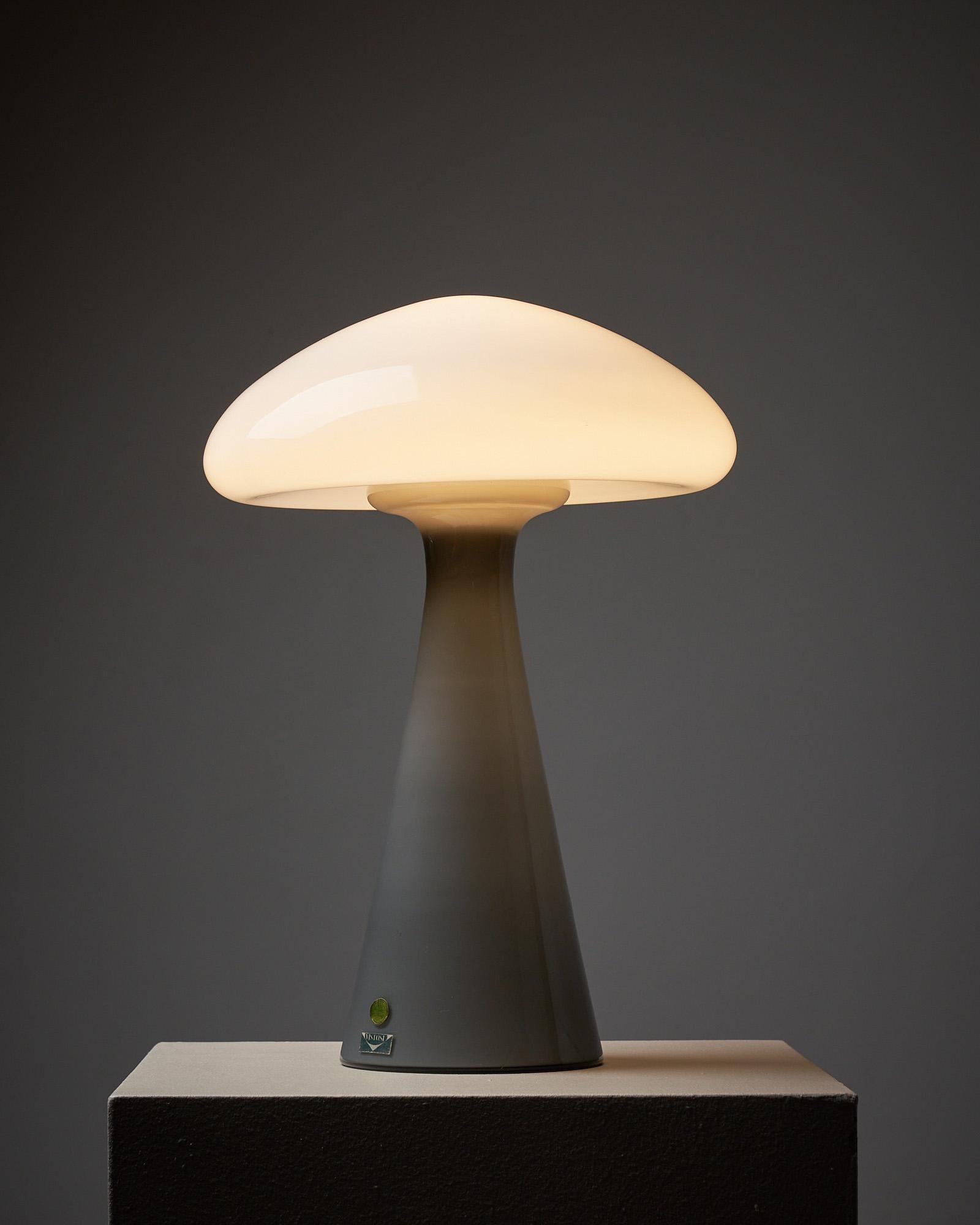 Introducing a unique table lamp by Vistosi, showcasing exceptional craftsmanship and design. This striking piece features a grey glass bottom and a white glass top that, when combined, resemble a mushroom form. The exquisite craftsmanship by Vistosi