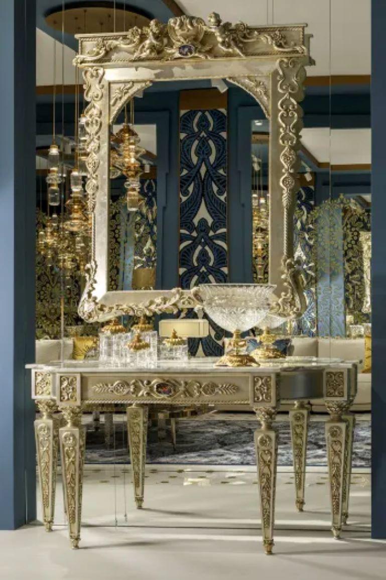 Console inspired by the Empire style characterised by square column legs with Doric-Corinthian capitals, carved decorations of garlands of leaves and rosettes.

Materials
In patinated silver champagne finish. Frame in Strobo Pine and Lime wood, top