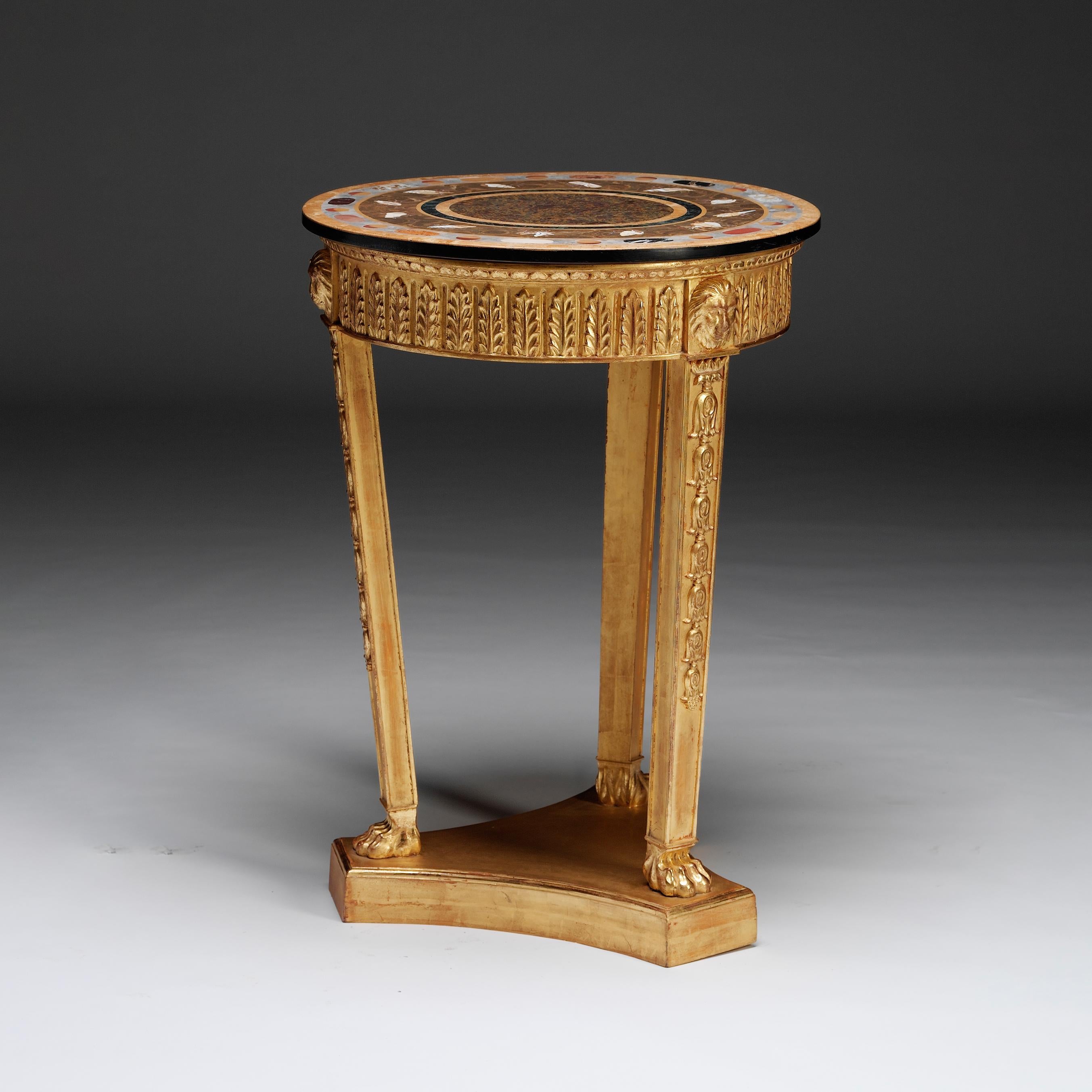 A carved gilt-wood ‘torchere’ in the Regency style. The exotic, circular marble top of concentric circles is inlaid with double bands of geometric shapes and seashells. The palm leaf decorated apron, punctuated by carved lion masks, is raised on