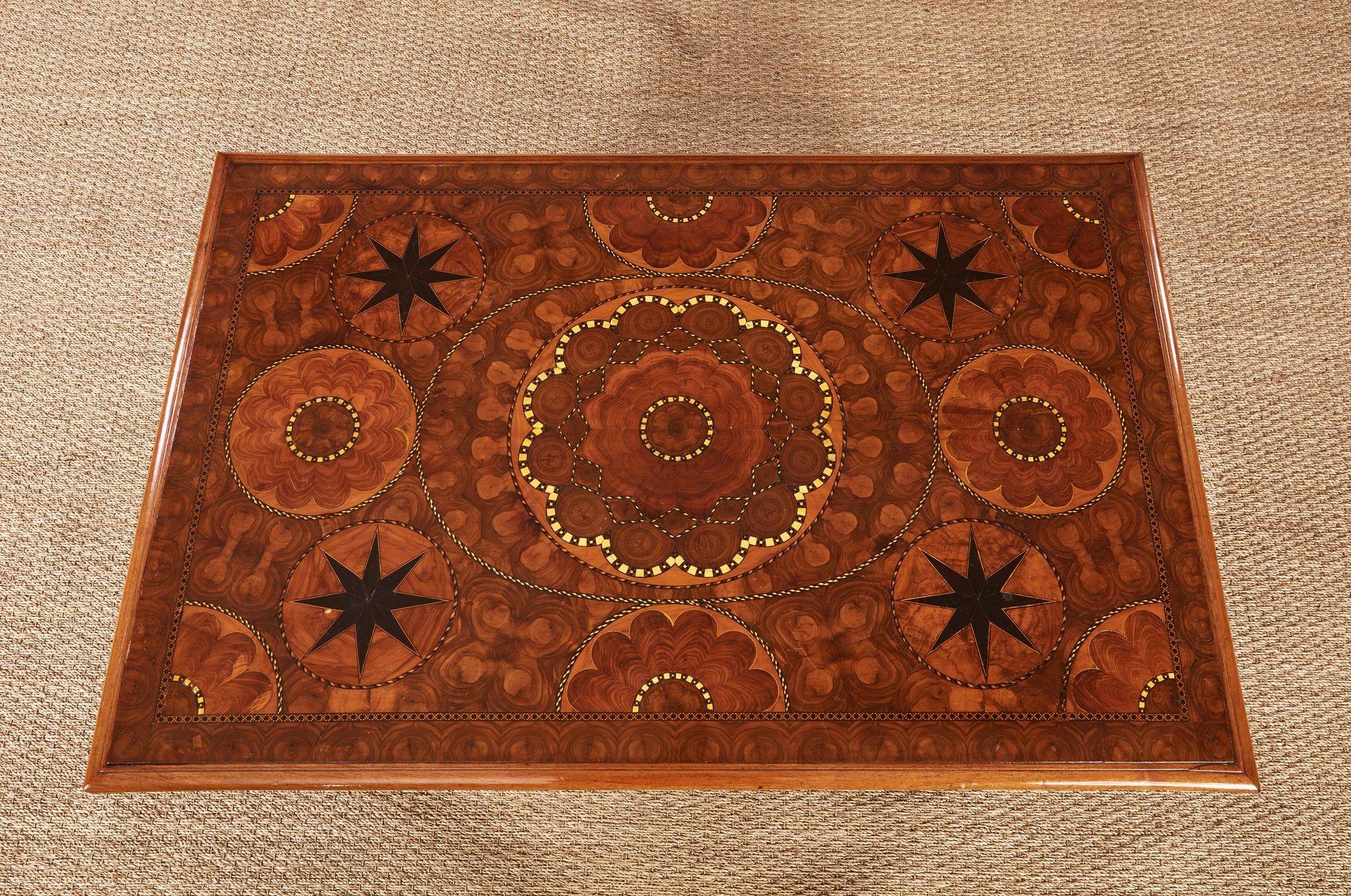 A low rectangular coffee table with stunning oyster veneered patera and star inlaid specimen wood top showing astonishing craftsmanship surrounded by a molded edge and raised on four barley sugar legs joined by an iron stretcher in a geometric oval