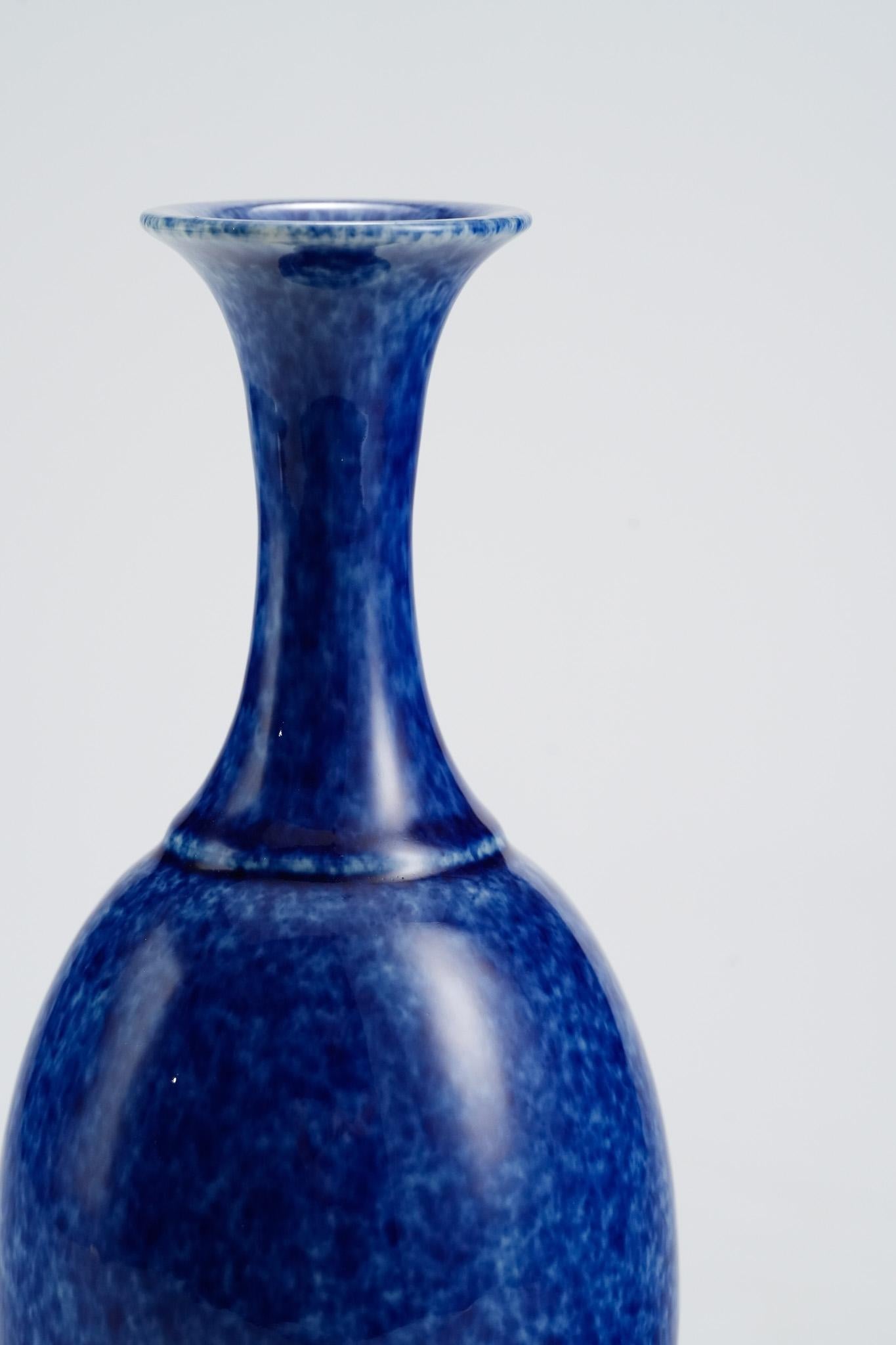 Questo vaso a collo lungo in porcellana di Shi Jie Weng è rifinito con uno smalto blu intenso pieno di morbide macchioline organiche. La superficie ricorda gli spruzzi dell'oceano sospesi in movimento o la neve che va alla deriva in un cielo