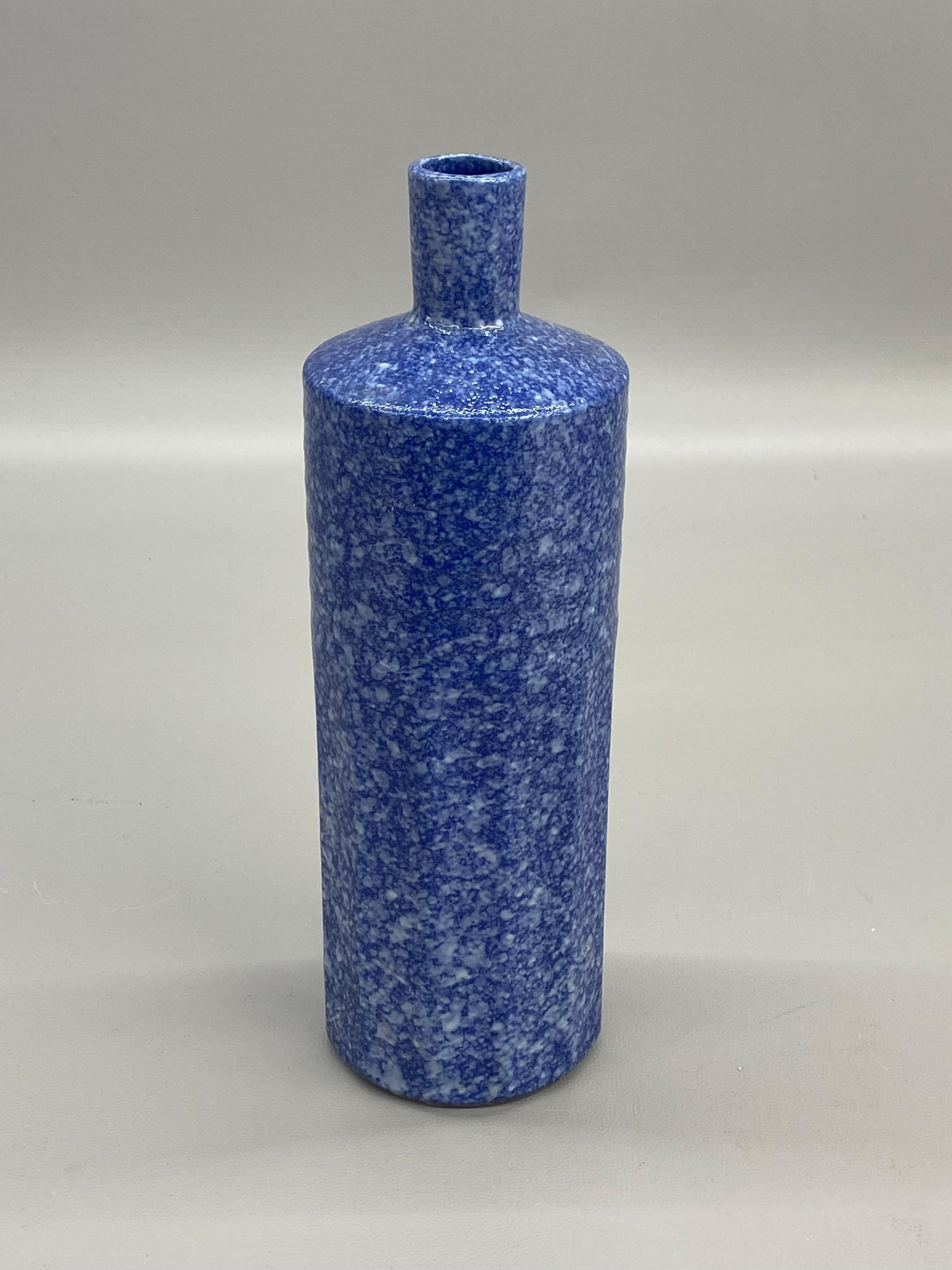 Vase en céramique de reproduction Williamstown, brillante et texturée, par Mann Japanese ceramics. Signé avec une étiquette ovale en feuille d'or, Mann, Japon. Fond bleu foncé avec surglaçage blanc moucheté. La forme A est une forme cylindrique avec