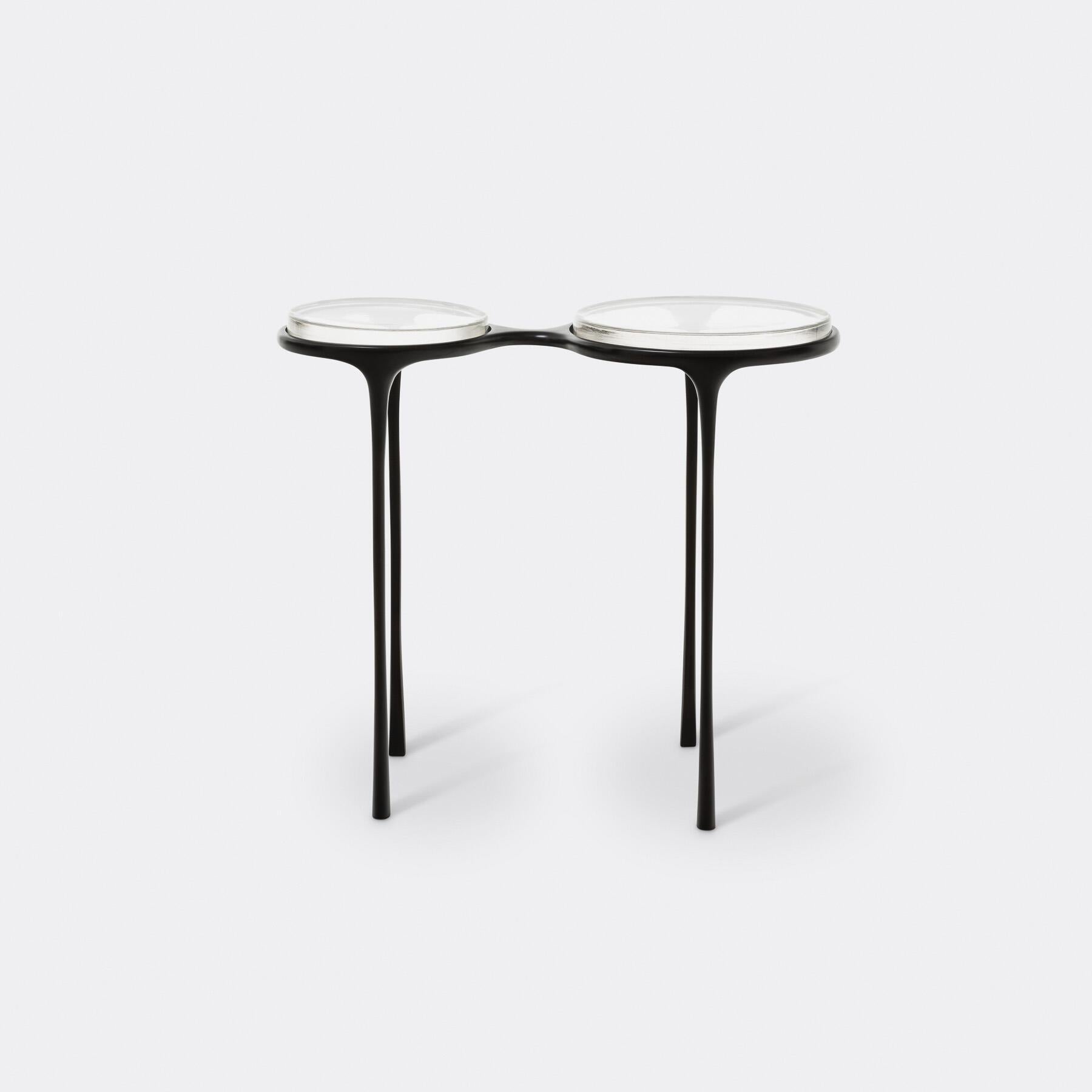 Inspirée d'une paire de lunettes vintage, la table d'appoint Spectacles est une vision unique du design qui prend vie. La base est en bronze moulé avec de fins pieds effilés, tandis que les deux surfaces sont dotées de plateaux en verre moulé. Que