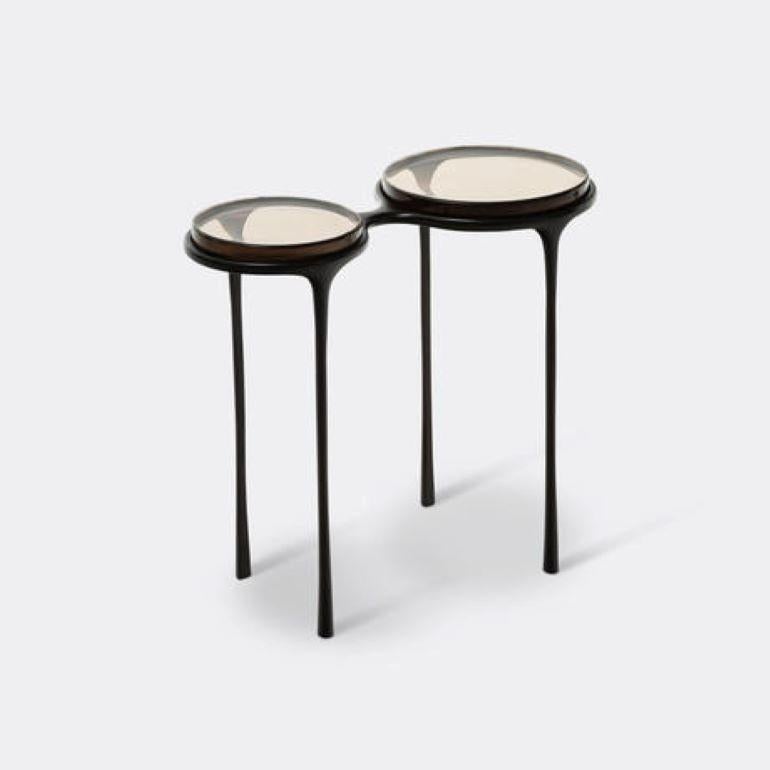 Inspired by a pair of vintage eyeglasses, the Spectacles Side Table is a unique design vision brought to life. The base is made of cast-bronze with thin tapered legs, while the dual surfaces are inset with cast-glass tops. Whether alongside a sofa