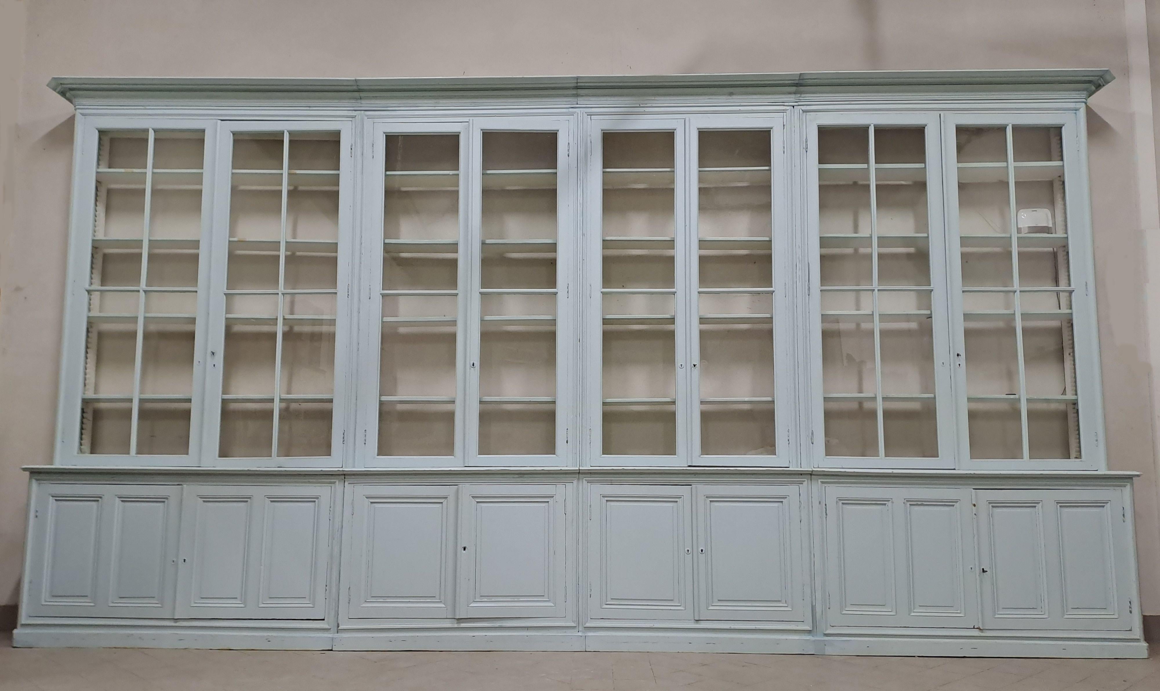 Very large bookcase in white/sky blue lacquered fir wood, opening with four double glass doors in the upper part and four solid double doors in the lower part.

19th century work, molded and paneled facades and sides, old glass.

Numerous solid wood