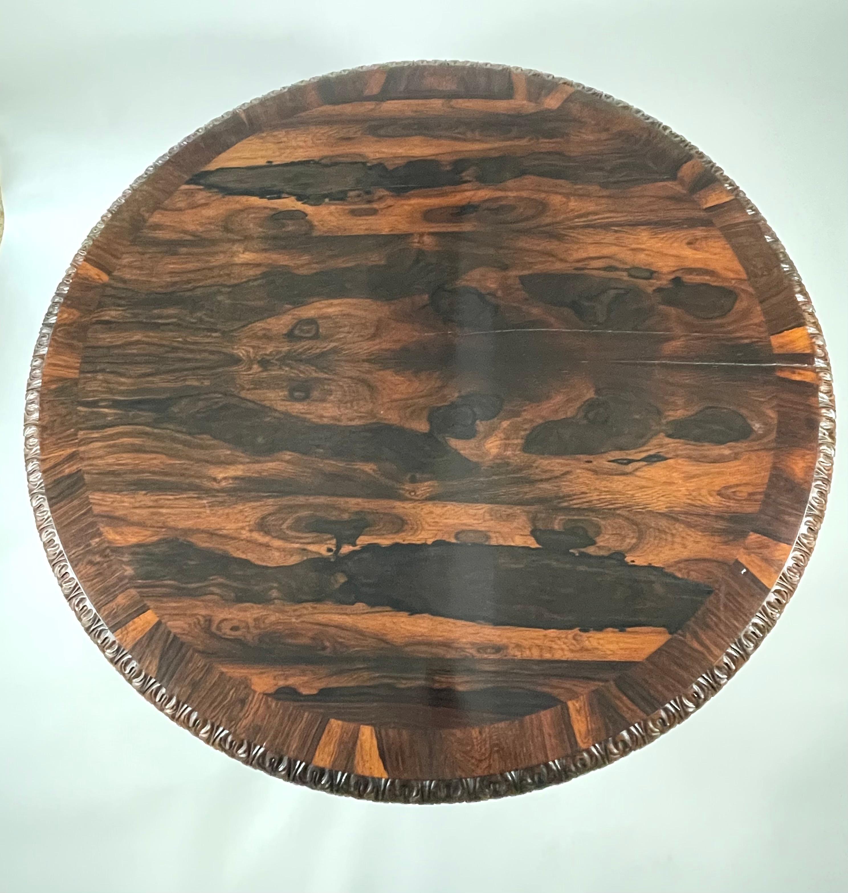 A fine quality, generously proportioned William IV rosewood center or dining table, the round top showcasing the extraordinary color and figure of the lively wood grain. It is edged with carved acanthus leaf decoration, supported by a pedestal with