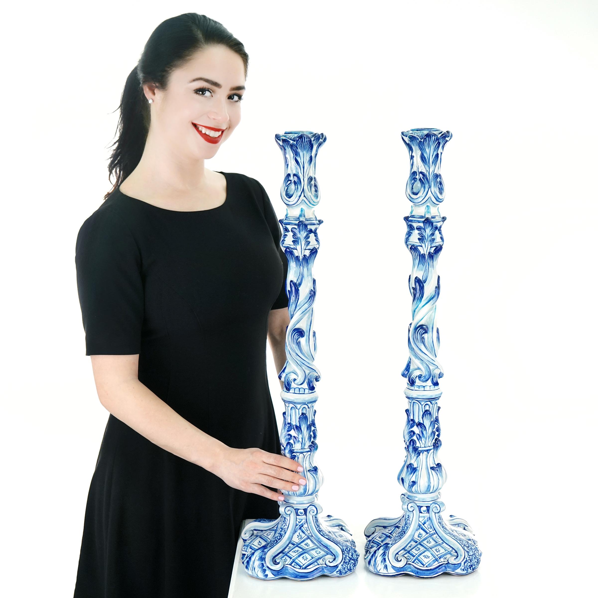 Circa 1913, France.  These stunning 28 inch tall blue and white faience candlesticks have an incredible country-meets-neoclassical look. Perfect for any décor, their style presages Deco while their scale is distinctly medieval. Excellent