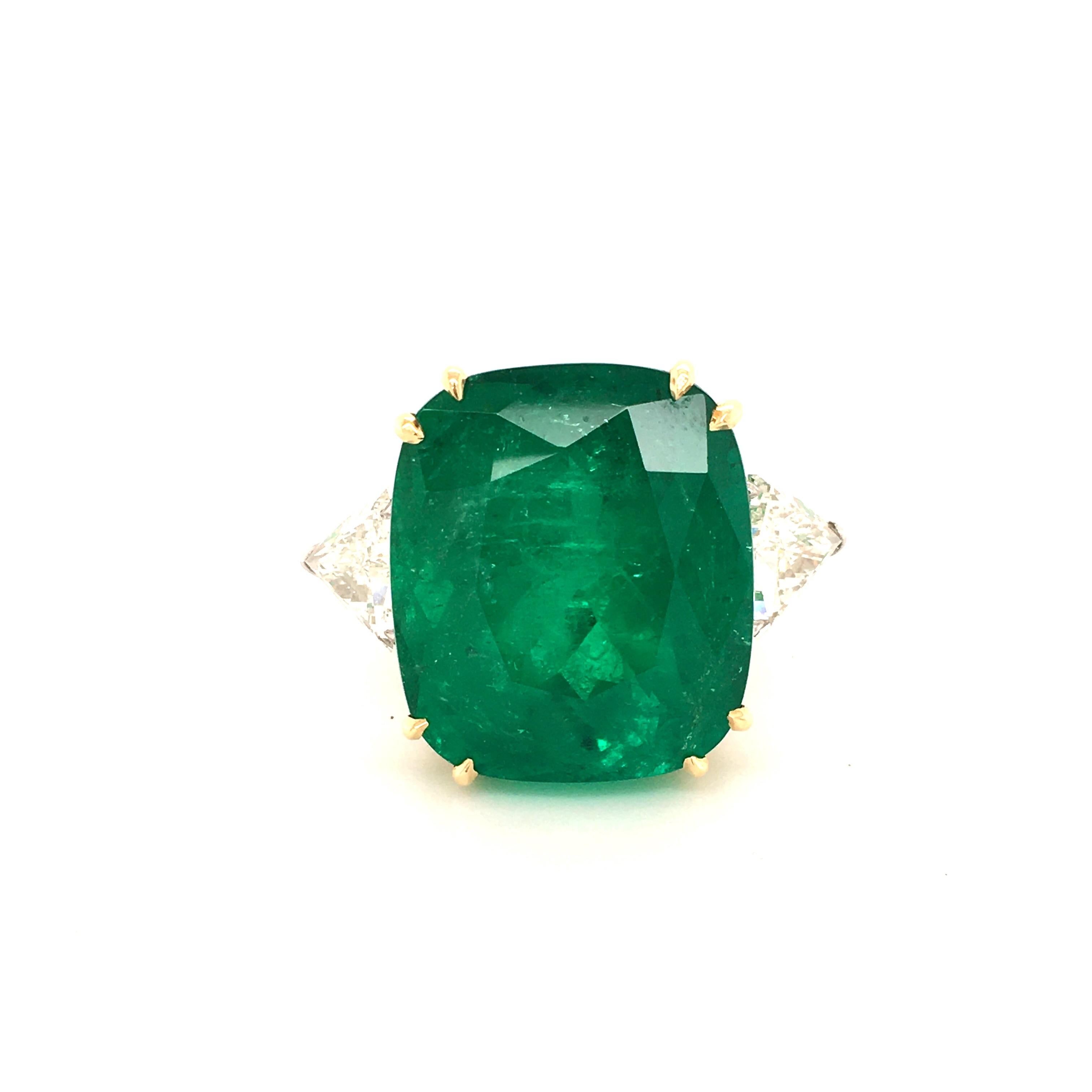 Dieser atemberaubende Ring ist mit einem kissenförmigen kolumbianischen Smaragd von 44,09 Karat besetzt, der eine wunderschöne intensive Farbe aufweist. Der Smaragd wird von zwei Diamanten im Dreiecksschliff mit der Farbe G/H und der Reinheit Si1