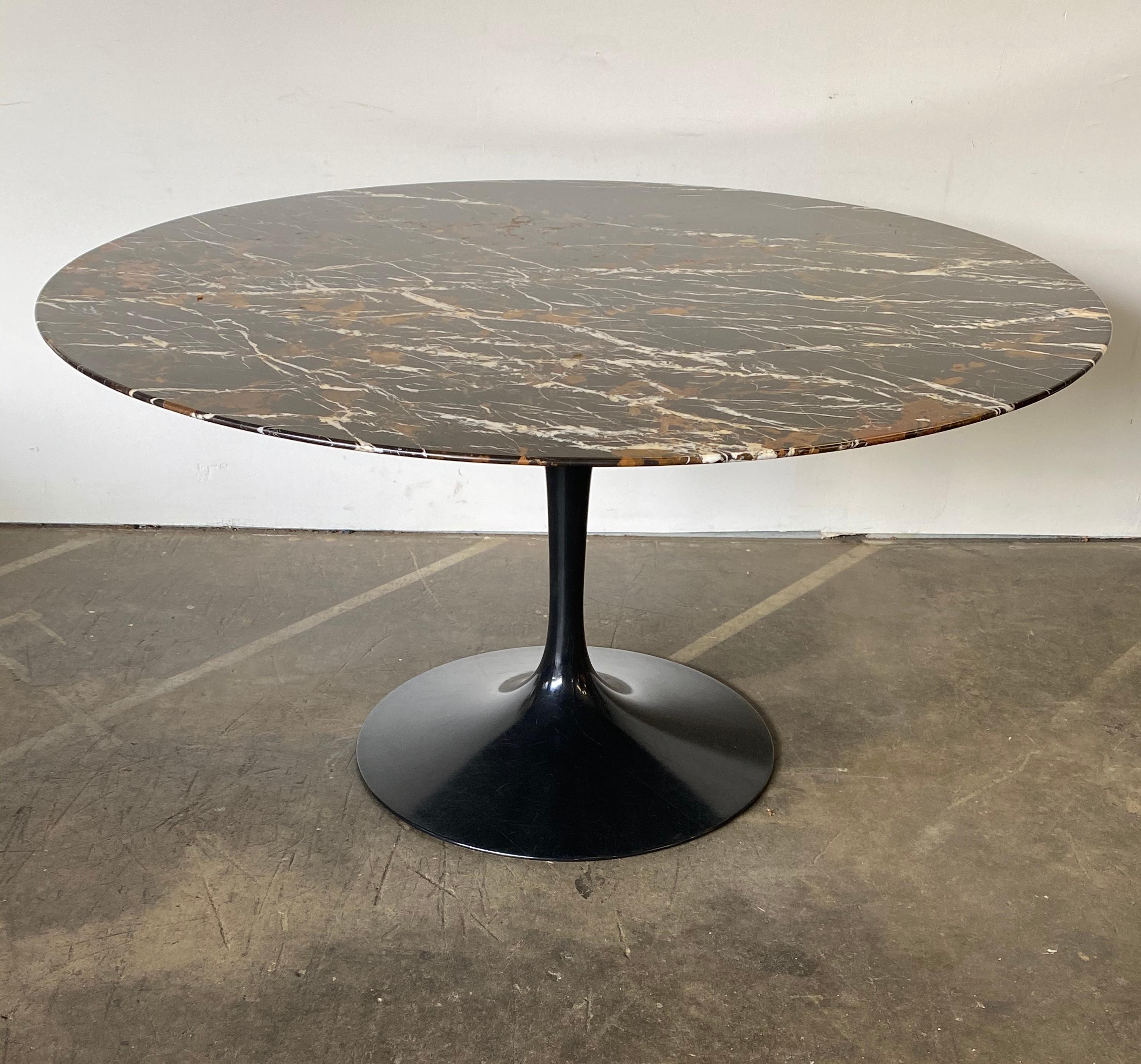 Spectacular round dining table by Eero Saarinen for Knoll. Signed and guaranteed authentic. Show stopping colors and veining adorn this marble slap atop black powder-coated aluminum base. Size: 54 inches in diameter. Accommodates 6 chairs.