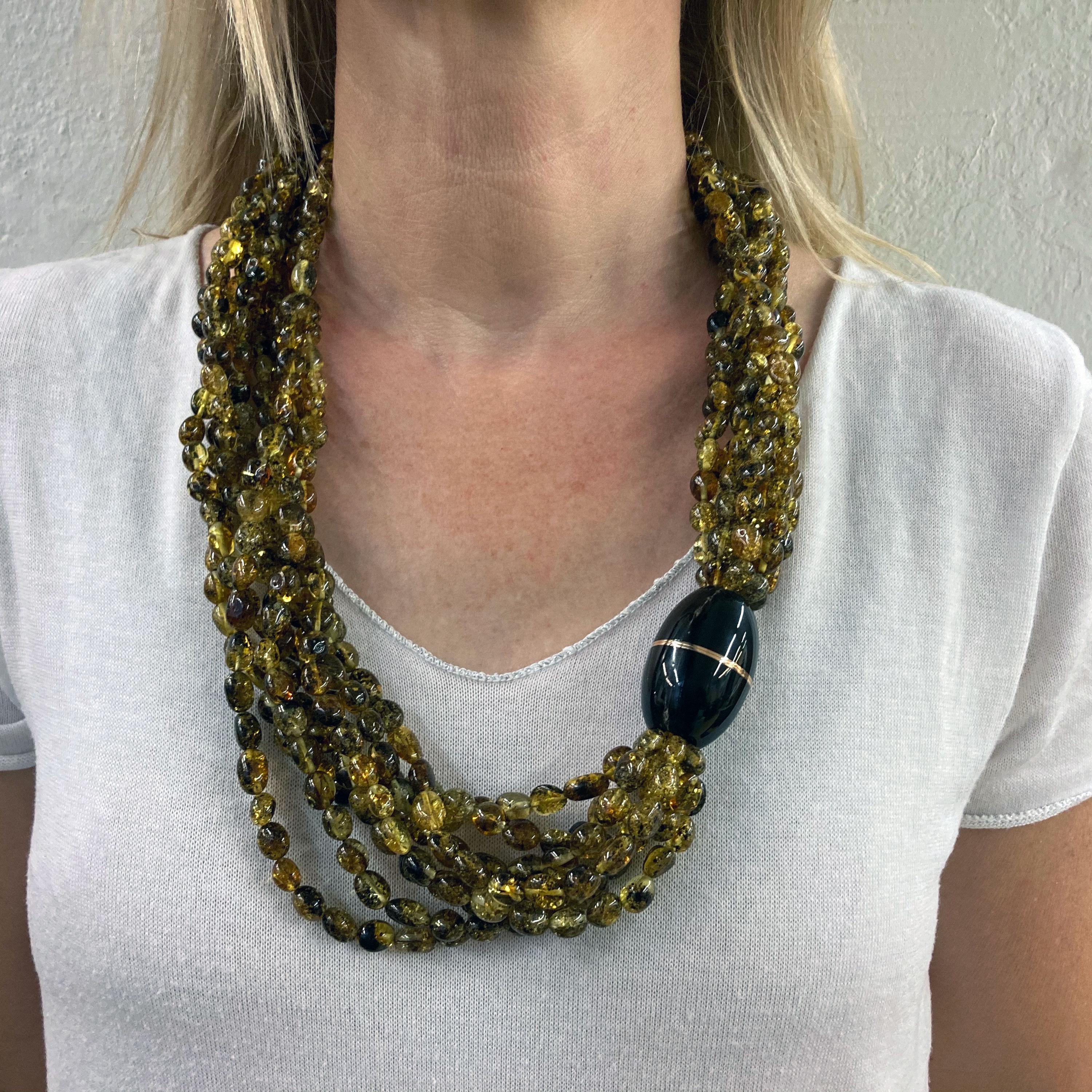 This outstanding 8 row necklace intrigues with the warm colors of the greenish yellow - brown Amber beads. The magnetic Closure is crafted in 18 Kt rose Gold and black Horn.
Although being very imporatant in size it is very comfortable to wear due