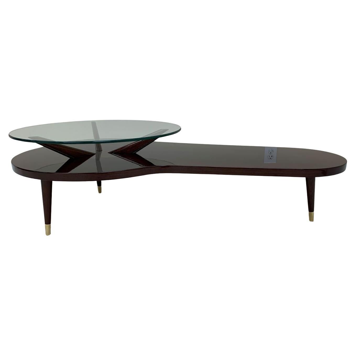 American Modern Biomorphic Mid Century cocktail table. Spectacular biomorphic design with a glass top circular end and an open radius end. Great attention to details noted with solid walnut legs adorned with polished brass caps. Dimensions 54.5