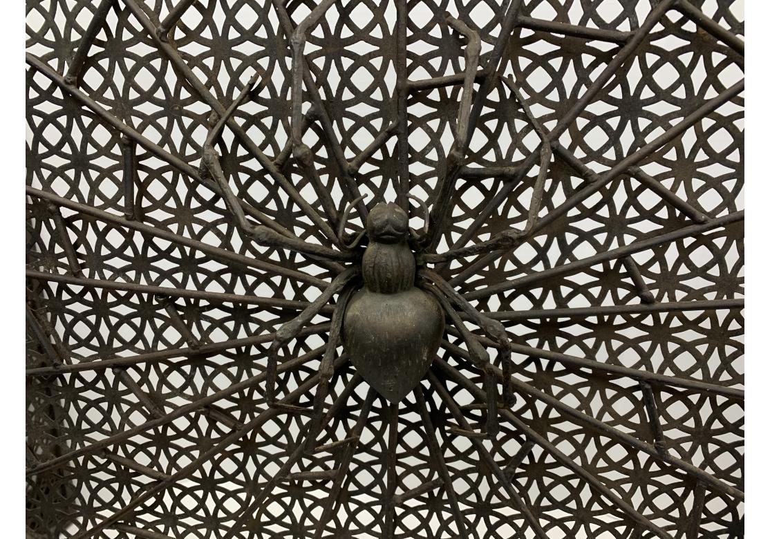 Biombo de hierro de tres paneles de la época de las Artes y Oficios, muy bien elaborado y de intrincado diseño. Una grande,  La araña, precisa y bellamente elaborada, está sentada en el centro de su telaraña sobre un fondo geométrico perforado