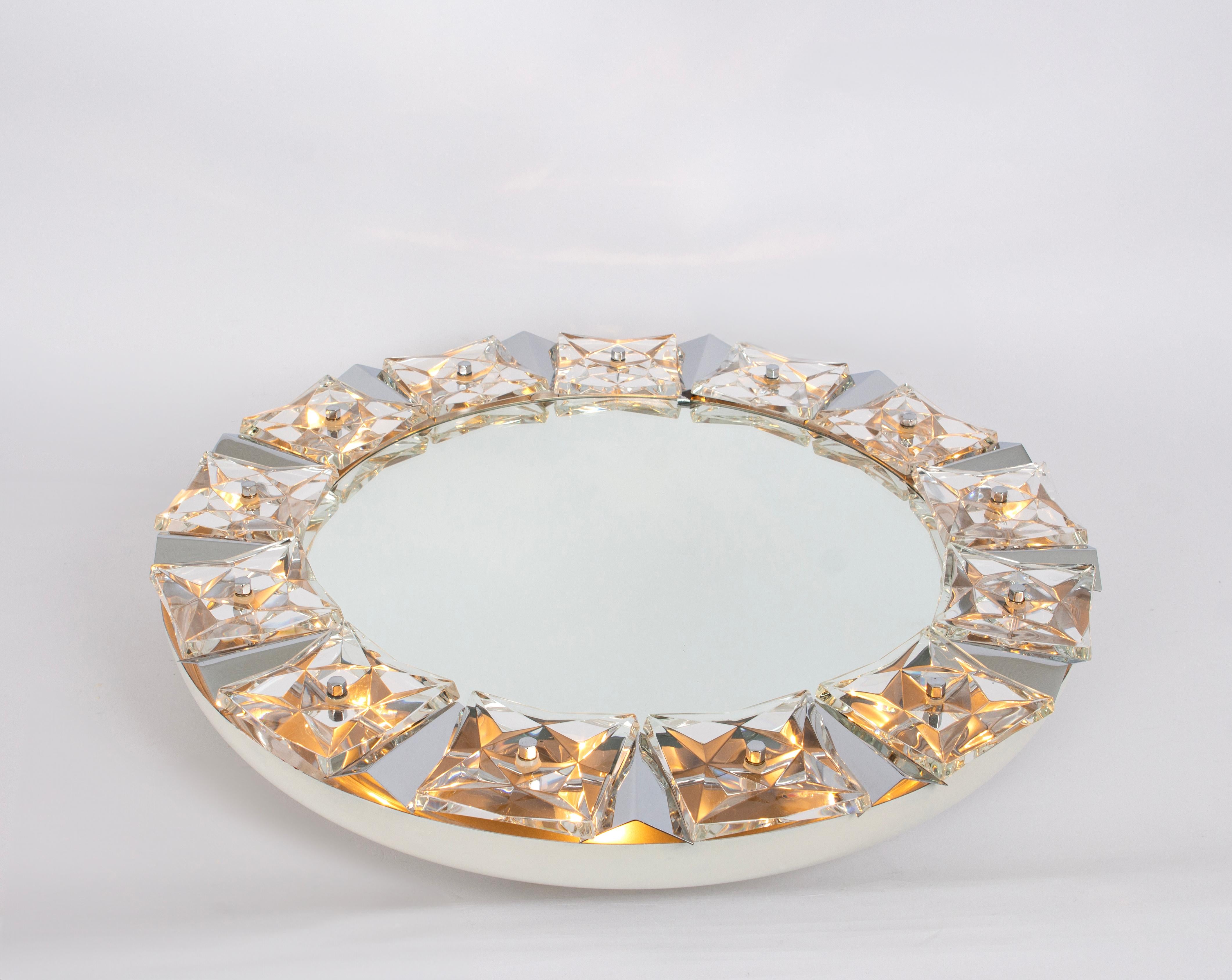 A wonderful and high quality wall mirror by Kinkeldey, Germany, 1970s
It is made of a chrome frame decorated with cut crystal glass. 

High quality and in very good condition. Cleaned, well-wired, and ready to use. 
The mirror can be illuminated and