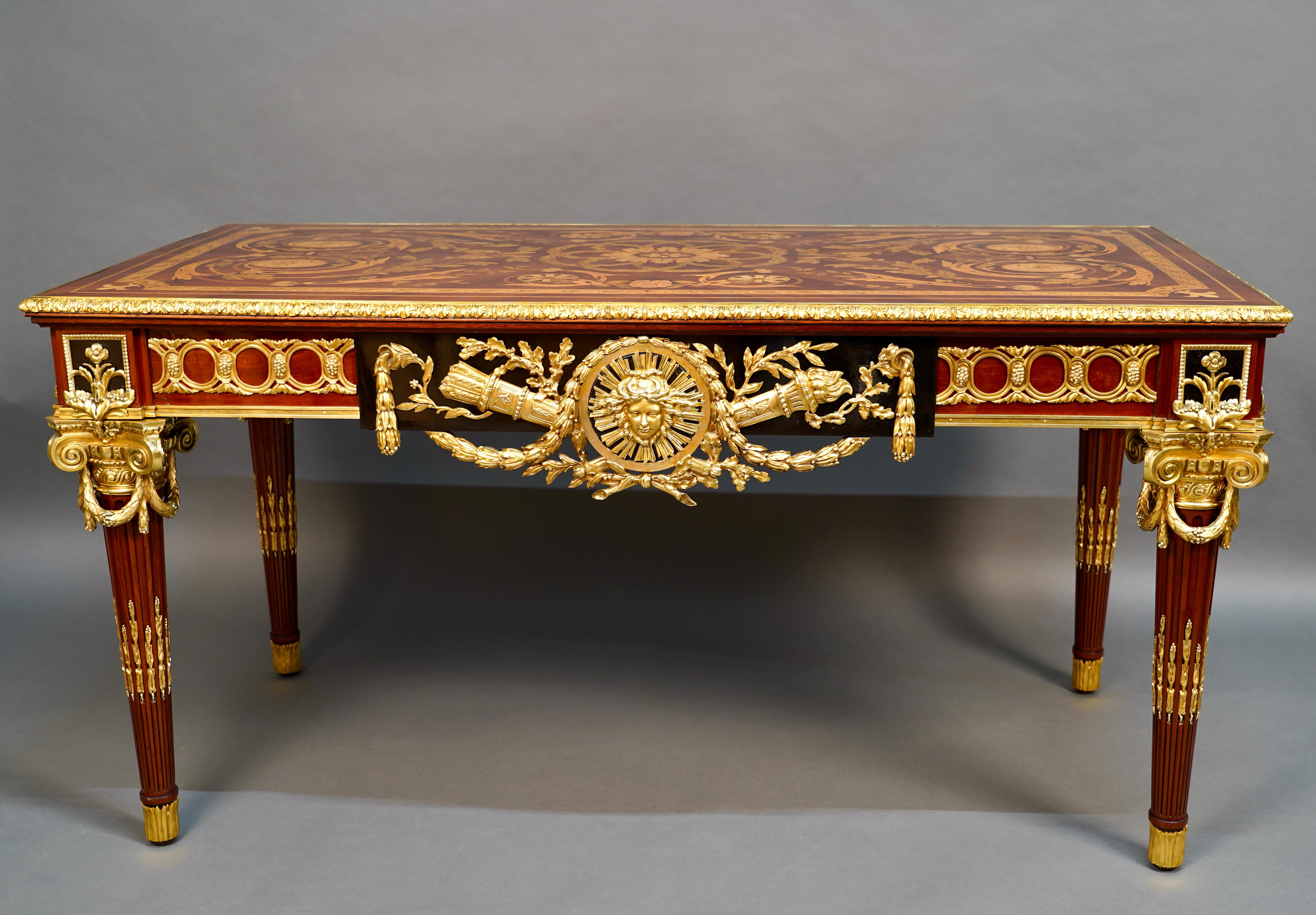 Beautiful ceremonial table in mahogany veneer, black stained wood and gilded bronze. The top with symmetrical decoration presents an important marquetry decoration of oak leaves, garlands and plant scrolls, embellished at the corners with