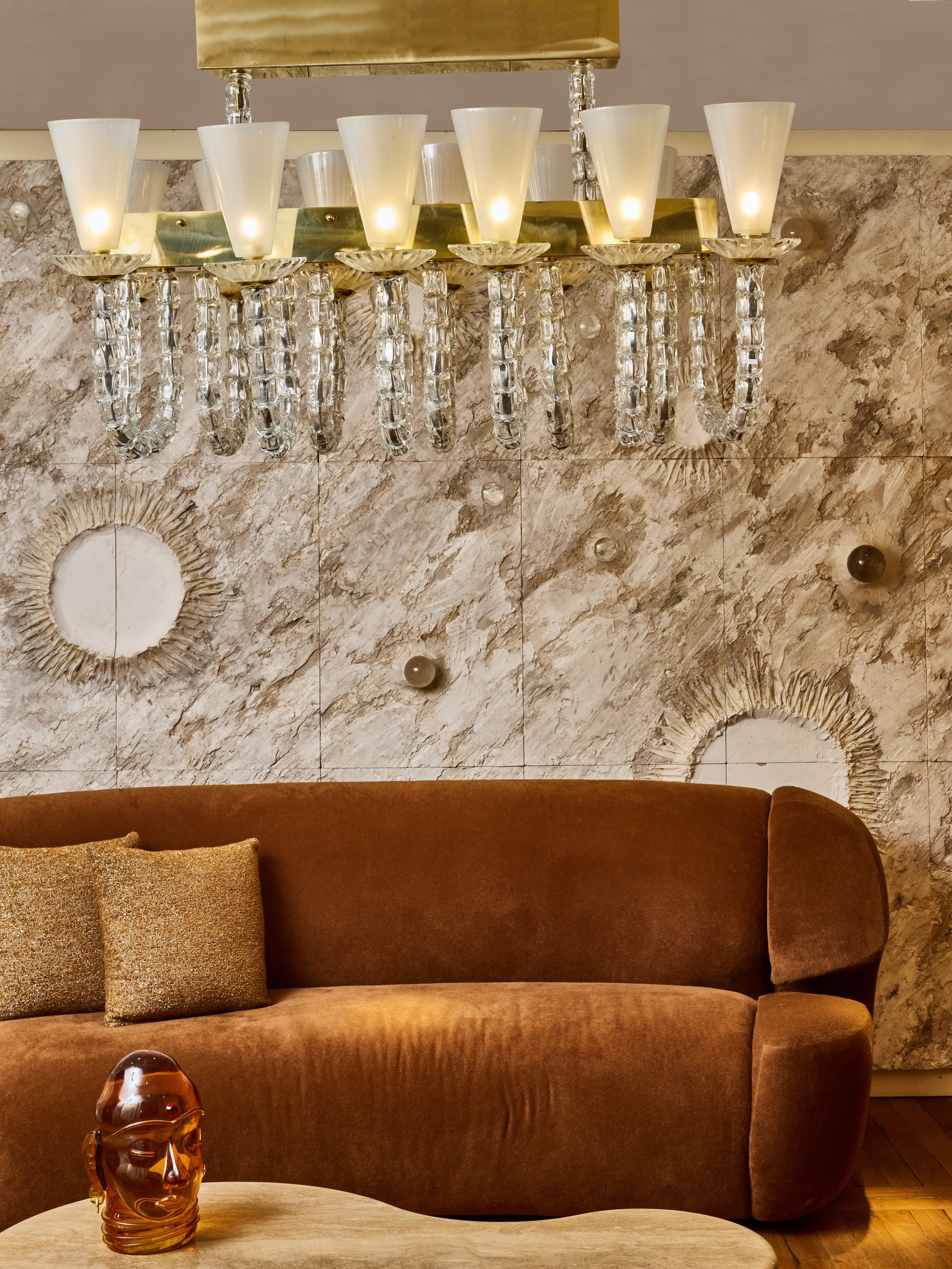 Lampadario lungo in ottone con 12 bracci in vetro di Murano scolpito e scaglie in opalina.
Creazione dello Studio Glustin.