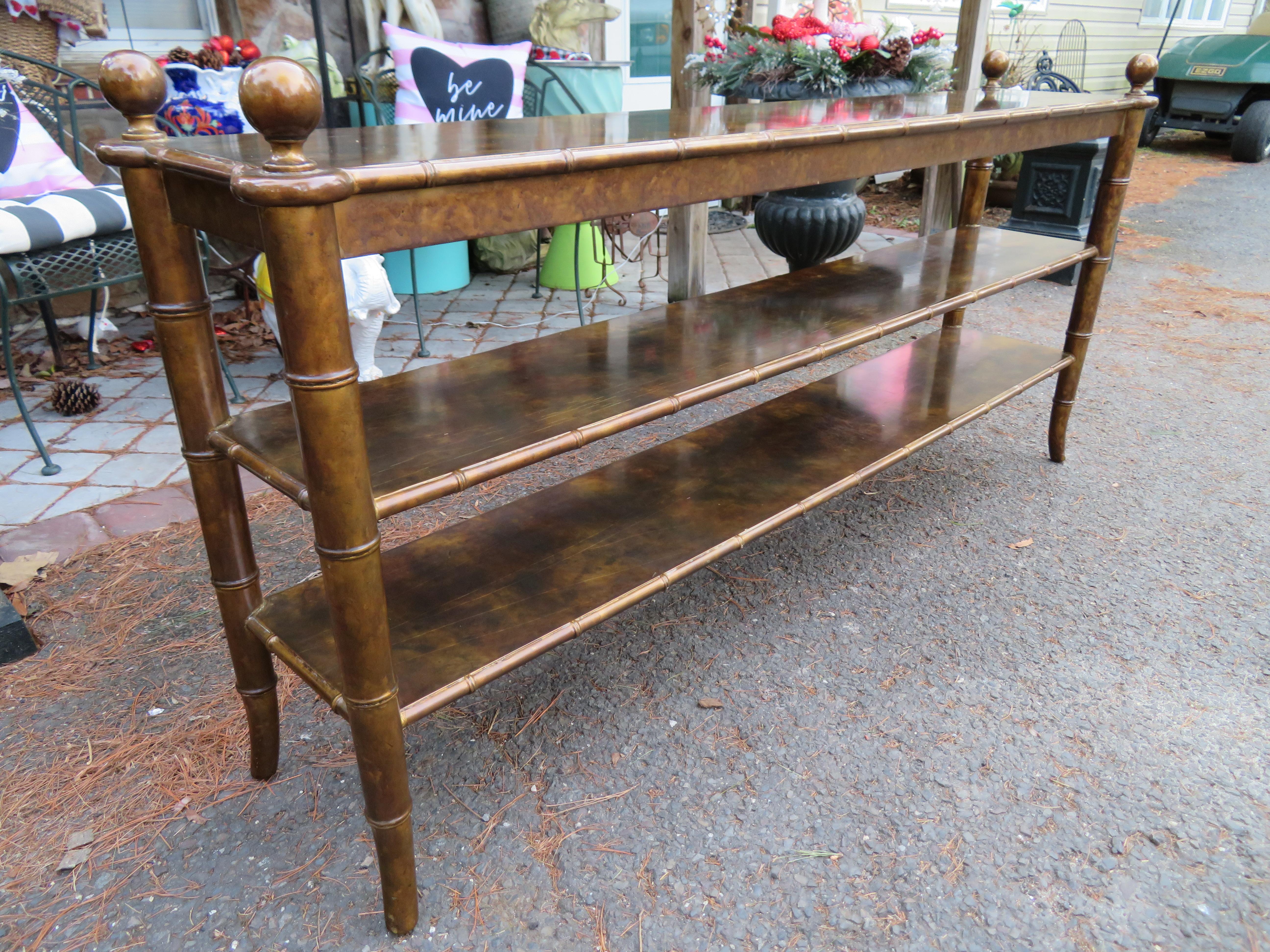 Mid-Century Chinoiserie long faux bamboo console table with a faux tortoiseshell high gloss lacquered finish.  We love the super long profile, the well-crafted carved faux bamboo legs, and the 3 tiers topped off with striking orbs on the corners. 