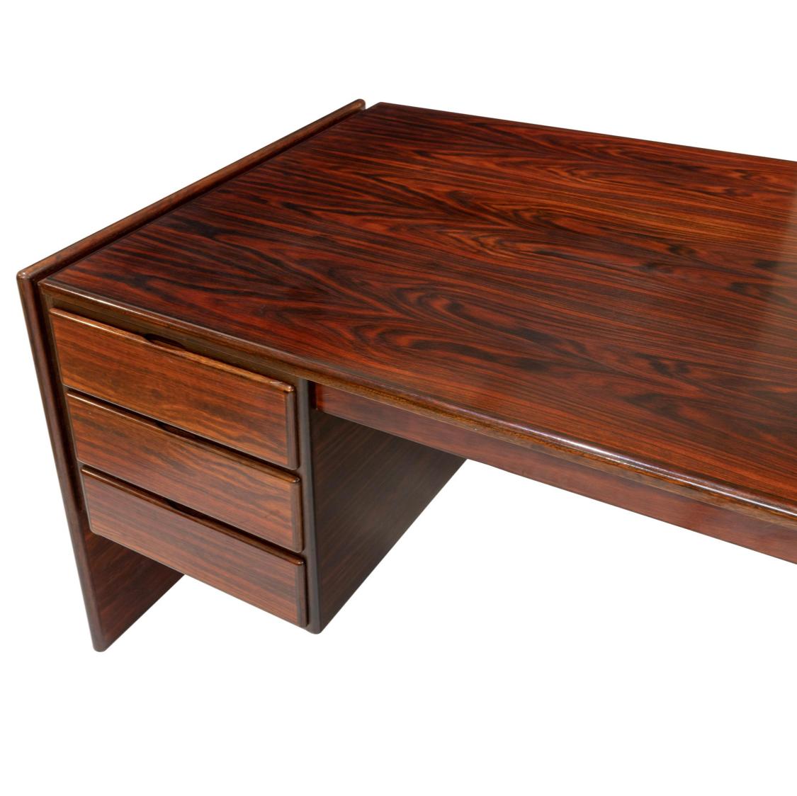 Spectacular Danish modern rosewood executive desk. Amazing depth of brilliant color and highly figured grain detail. Due to environmental regulations rosewood is no longer allowed to be used for furniture production. Simple yet striking minimal