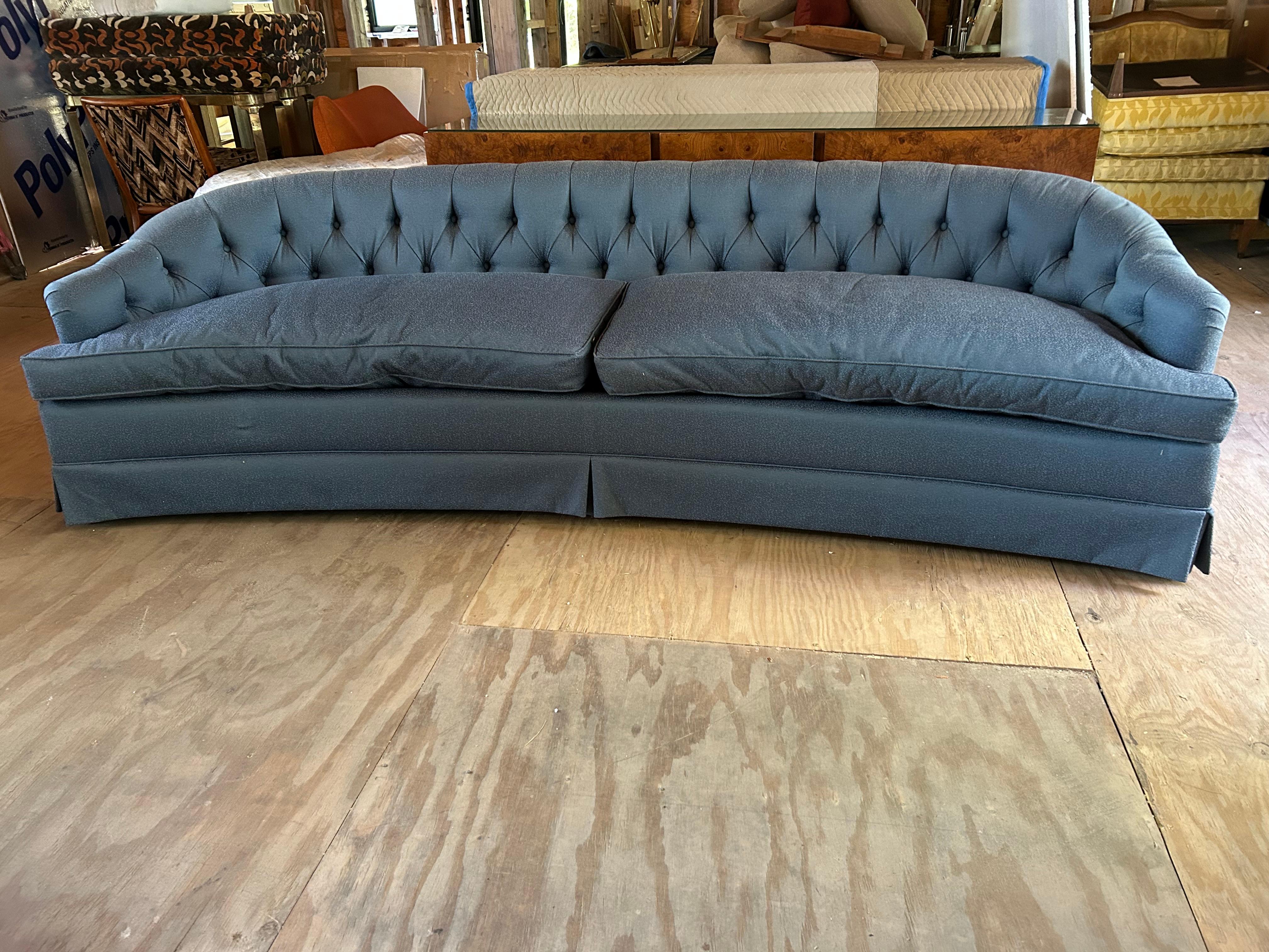 Add vintage charm to your living room with this sophisticated Dorothy Draper style Hollywood Regency tufted curved sofa. Upholstered in a vintage textured blue fabric, the sofa boasts a button-tufted backrest and elegant low-profile design, perfect