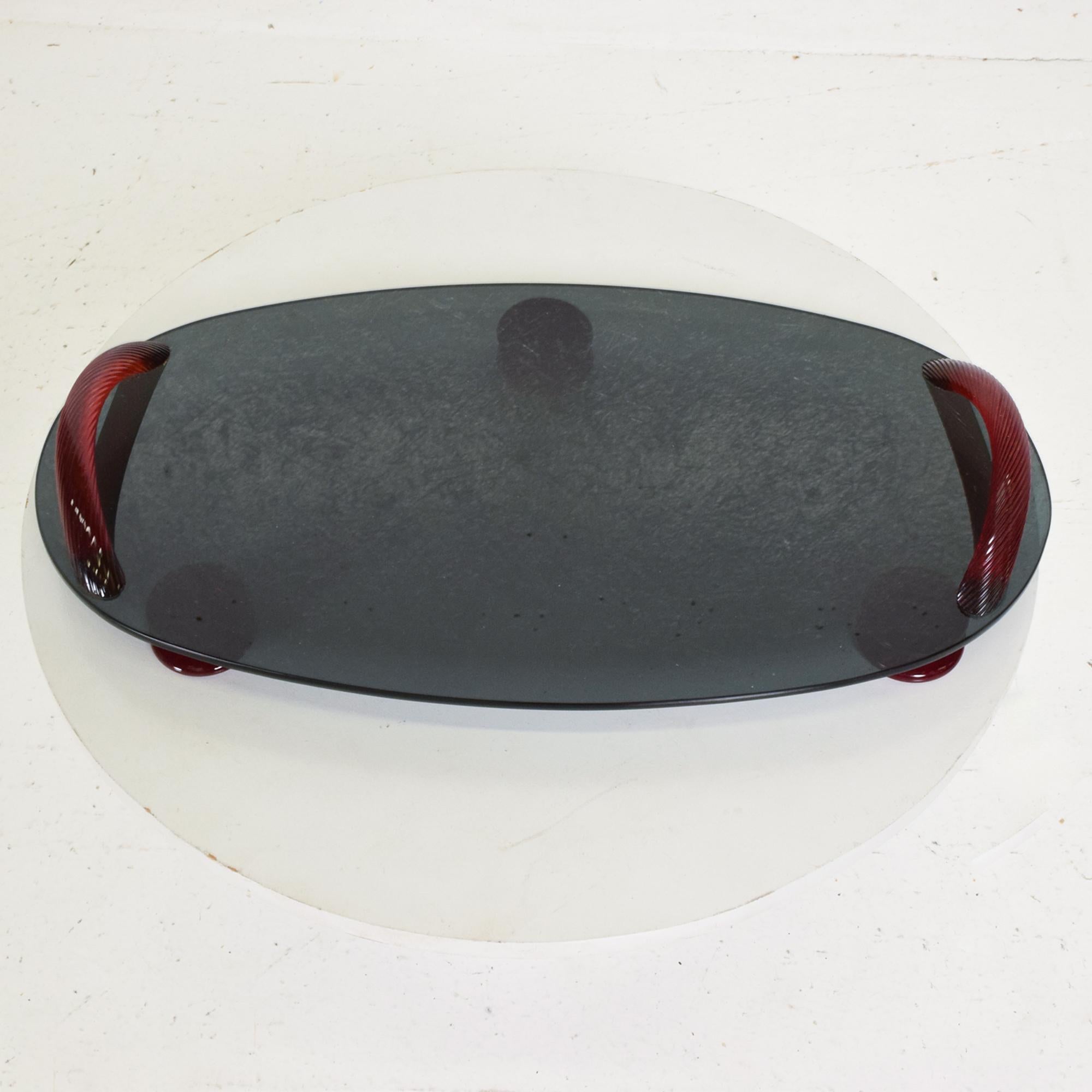 Glass Tray
Post Modern Oval Platter Serving Dish Footed Tray in Smoke Glass with Ruby Red Glass Carry Handles
Fabulous modern design with stylish carry handles and matching feet.
In the style of Seguso Vetri d'Arte. 
Signed on one side we are unable