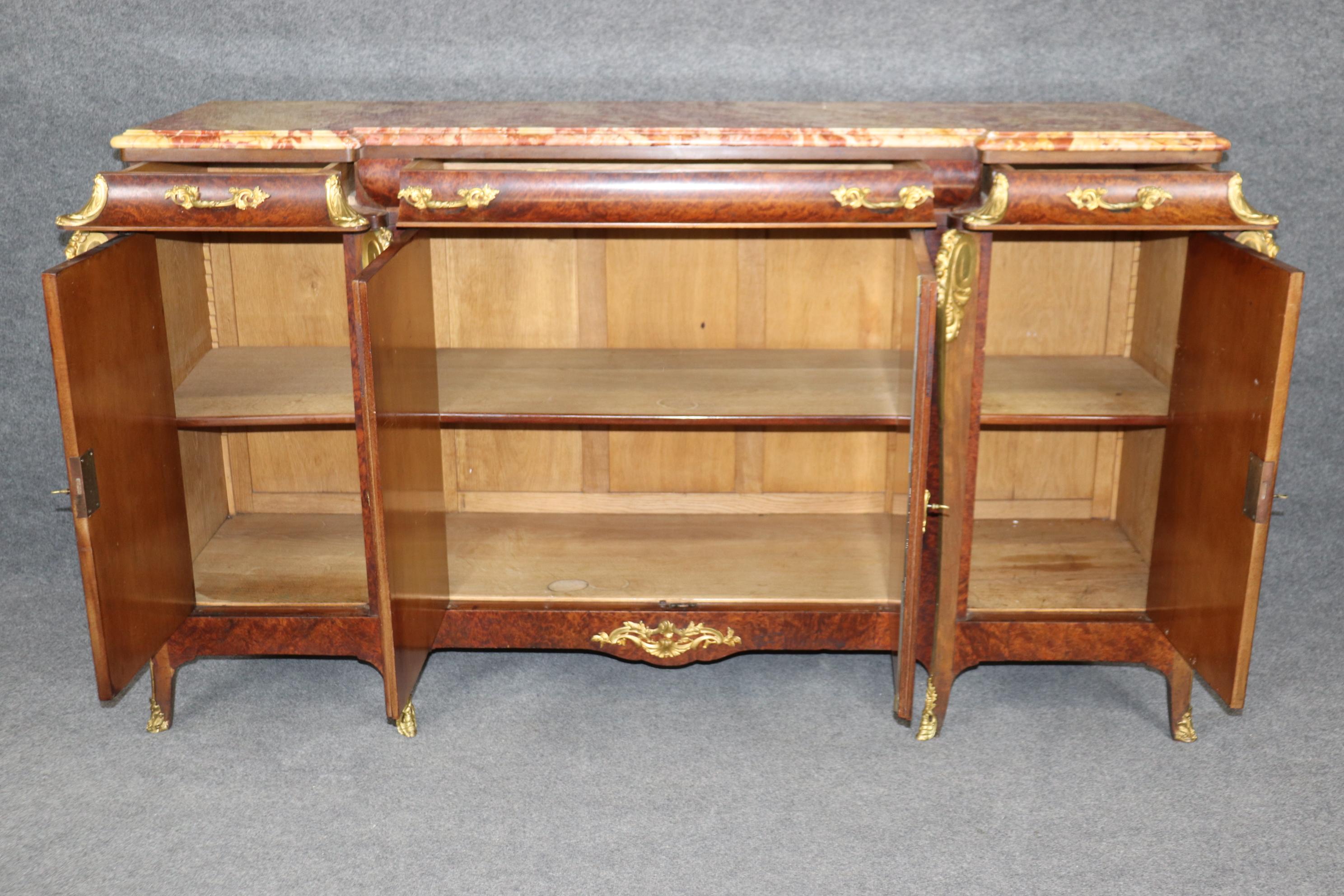 Dies ist ein spektakuläres und hervorragend verarbeitetes Sideboard. Sehen Sie sich die Marmorplatte und die einzigartige Symphonie aus Braun-, Rot-, Creme- und Off-White-Tönen an. Das Stück ist aus massivem Nussbaumholz mit unglaublich gemasertem