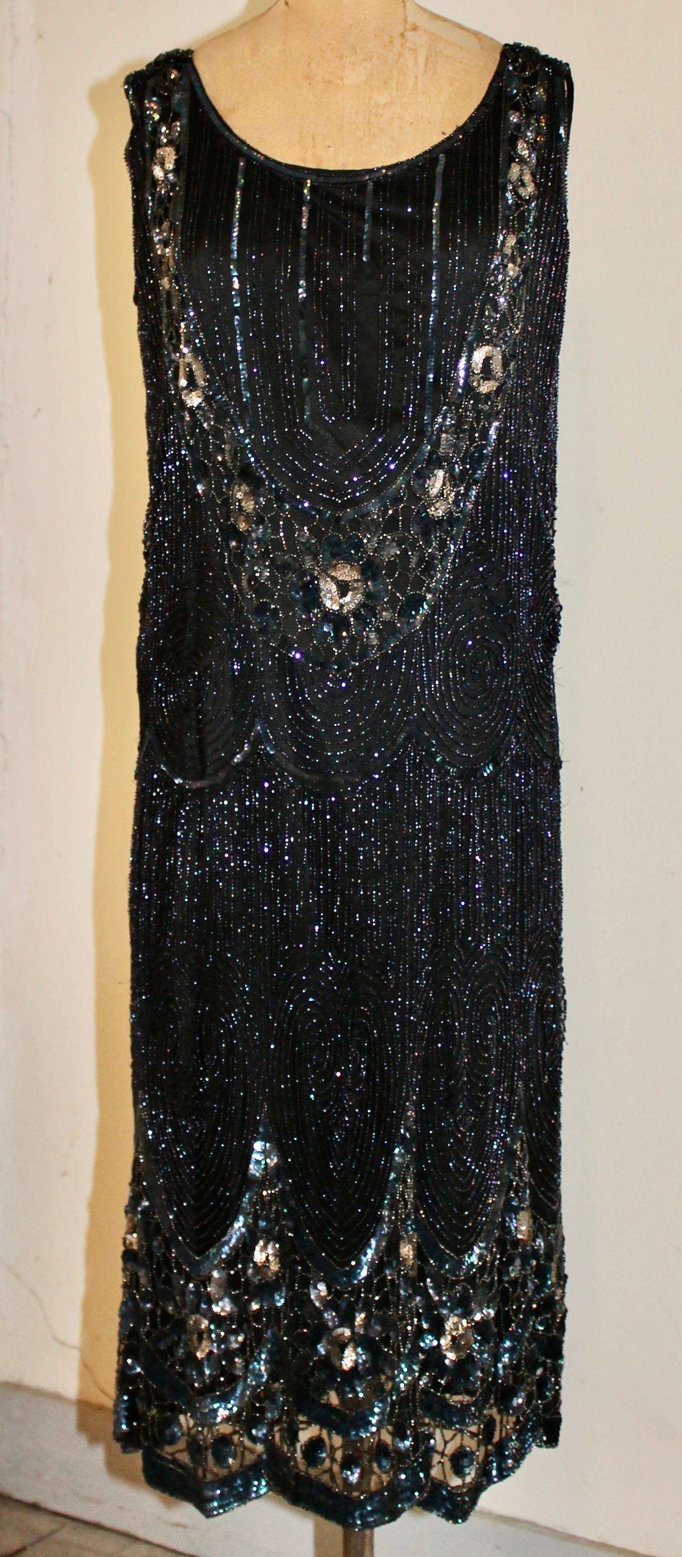 Gaze de soie noire, fortement brodée de paillettes irridiées créant des motifs complexes et tourbillonnants soulignés par des fleurs irridiées densément brodées. L'abondante ornementation de paillettes multi-métalliques crée un effet magique de