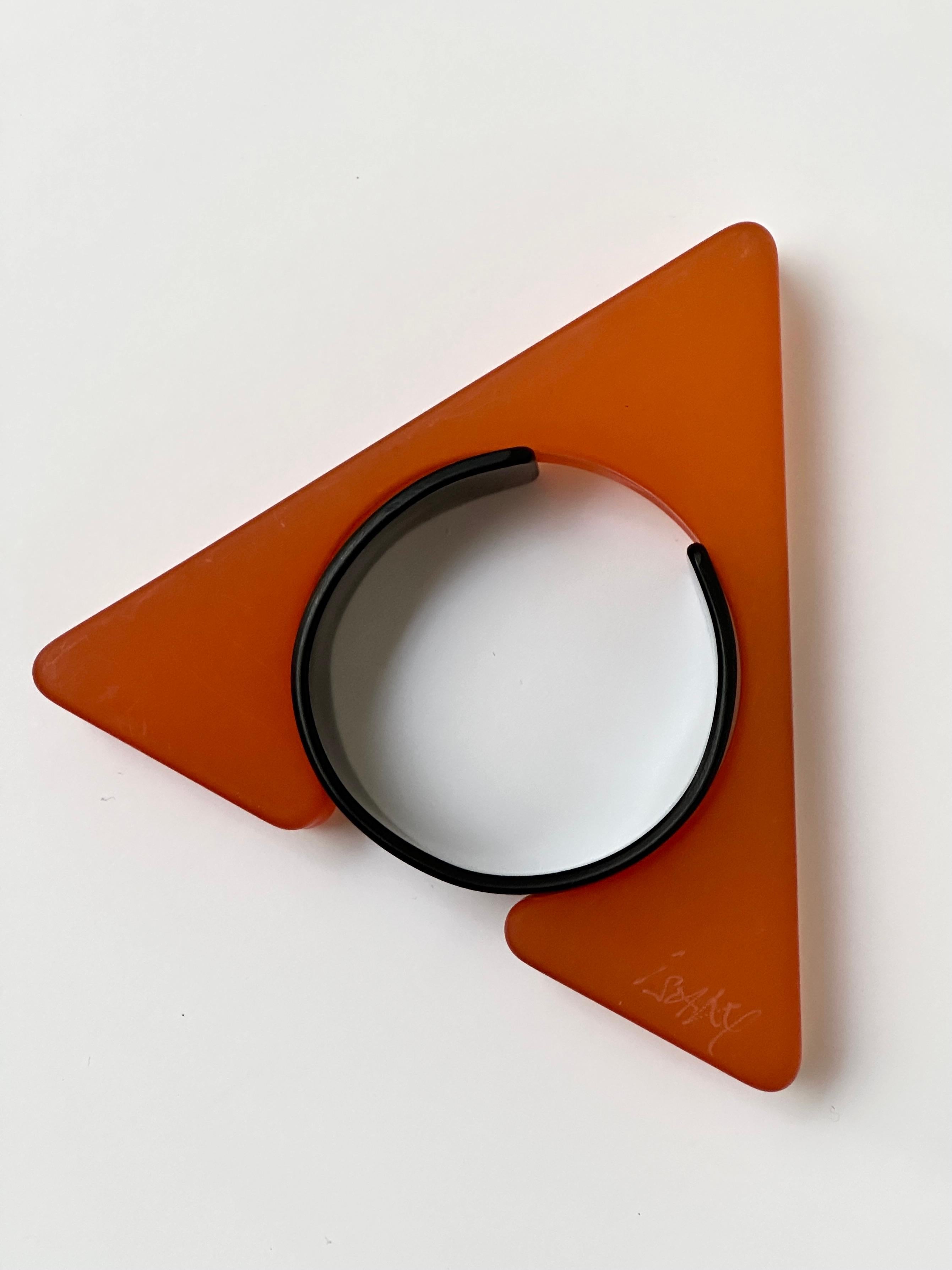 Half object, half jewel this sculptural bangle is composed of two parts ; a sand blasted resin triangle and an acrylic bracelet allowing the cuff to be closed.
Both parts bear the handwritten and engraved signature of the artist.

Measurements (cm)