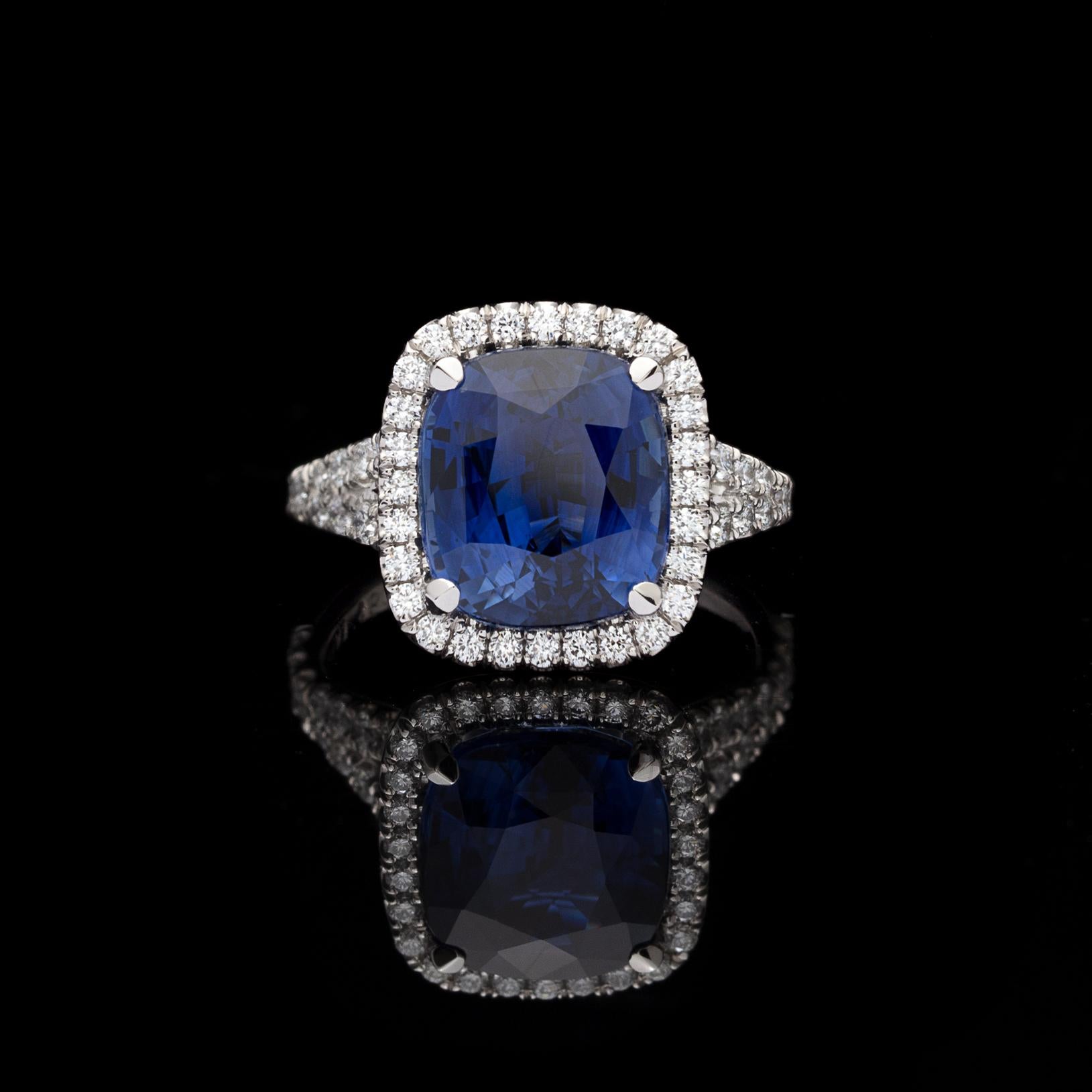 A gorgeous platinum ring boasting a rare unheated 7.06 carats cushion-cut blue sapphire, surrounded by a halo of brilliant-cut diamonds and diamond-set split shank, for a total diamond weight of 0.72 carat. The ring is currently size 6 1/4, with
