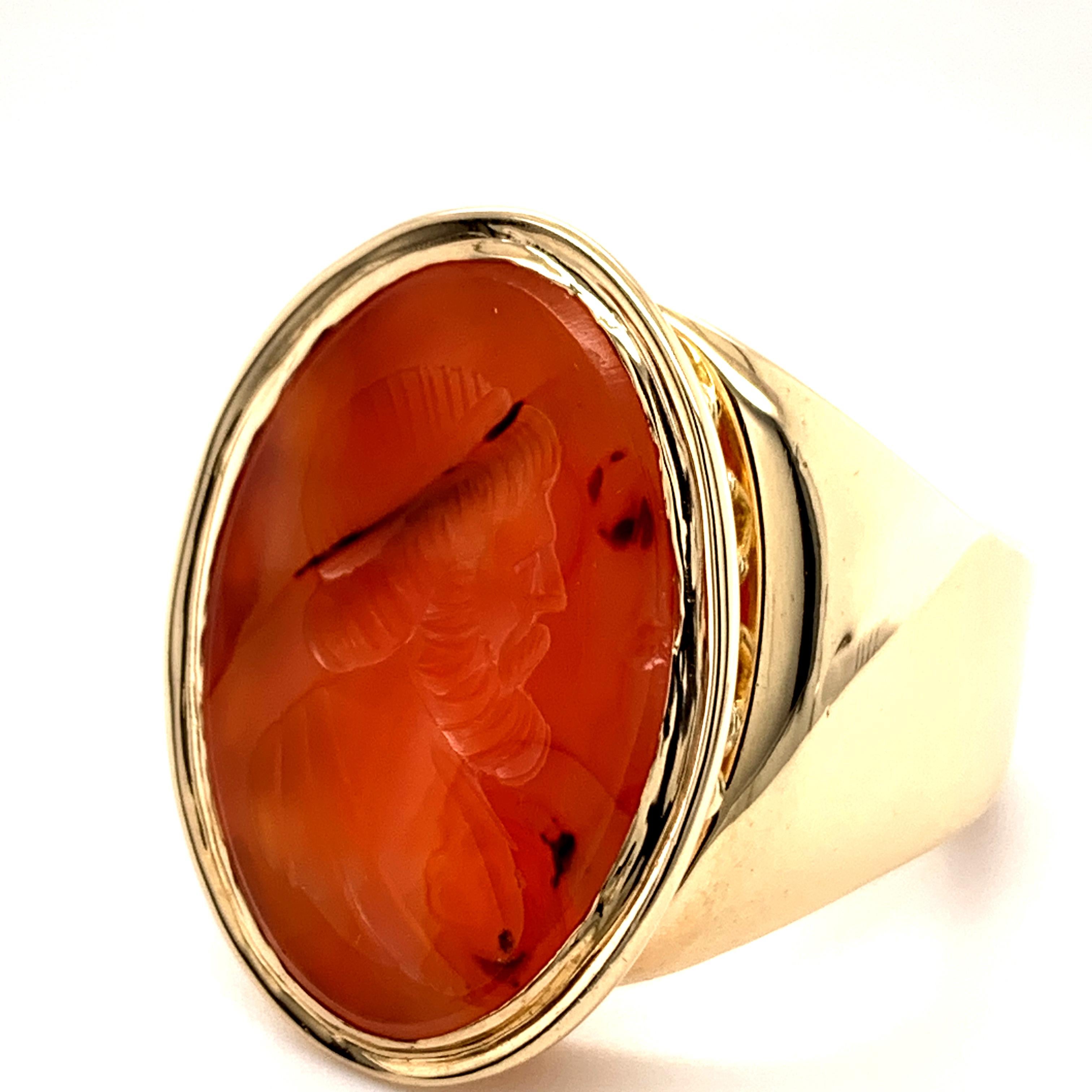 Very large and dramatic crest ring.  Oval shape.  The center is a deeply carved carnelian Roman head.  Set in a solid gauge 14K yellow gold mounting.  Size 12 and can be custom sized.  The front of the ring measures 3/4
