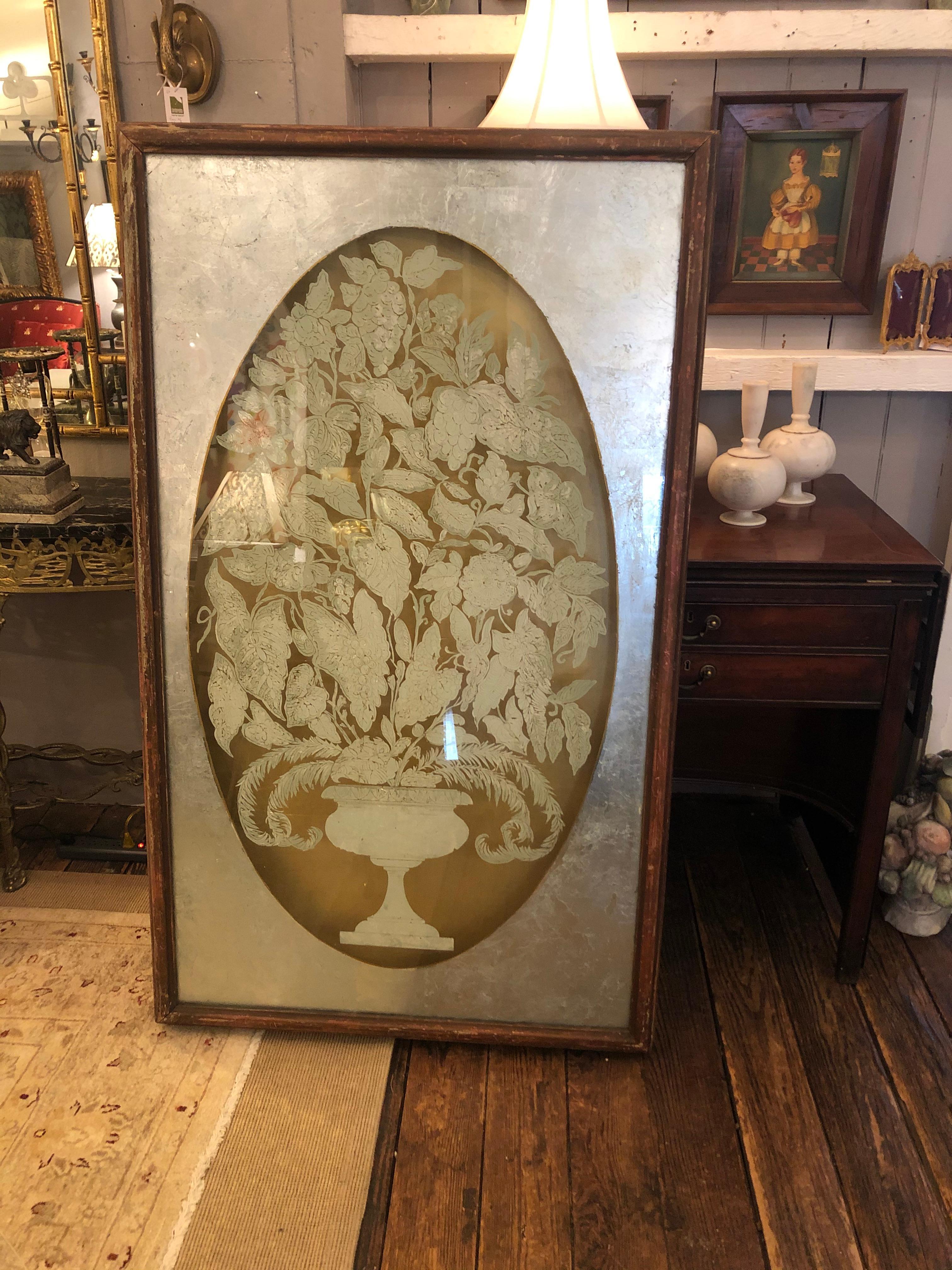 One of a kind amazingly elegant dramatic pair of reverse painting on glass panels in deep 3 dimensional distressed wooden frames. Gold leaf backgrounds allow light to glisten behind the frontal paintings of oval silver leaf floral arrangements with