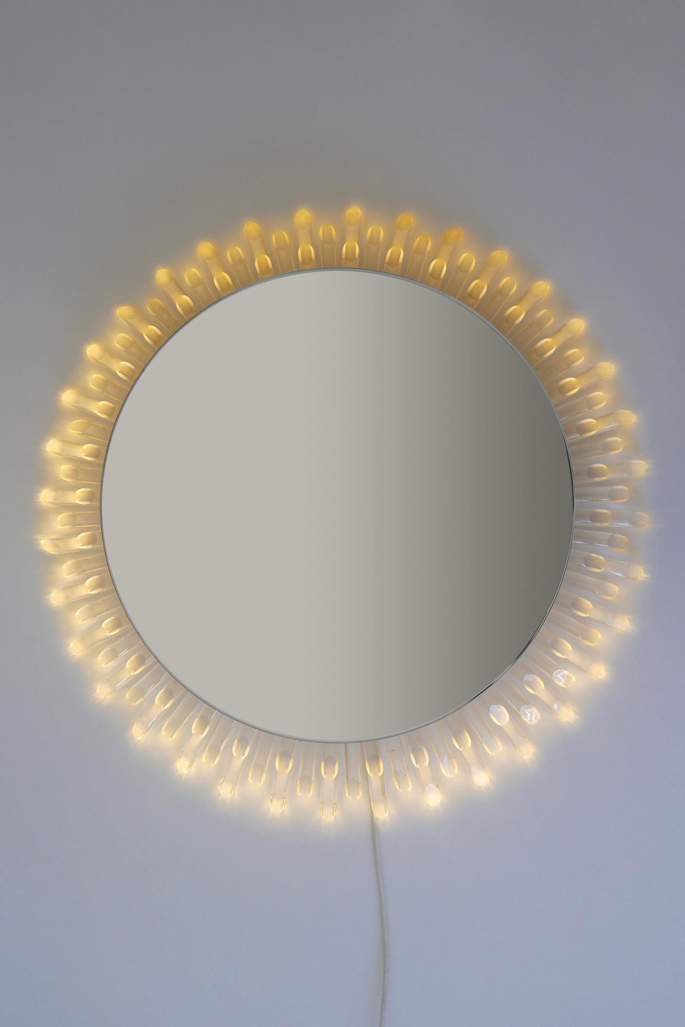 Un véritable bijou pour votre maison ! Rarissime, élégant et grand miroir mural circulaire rétro-éclairé en forme de soleil de la modernité du milieu du siècle. Conçue et fabriquée probablement en Allemagne, dans les années 1970

Il produit des