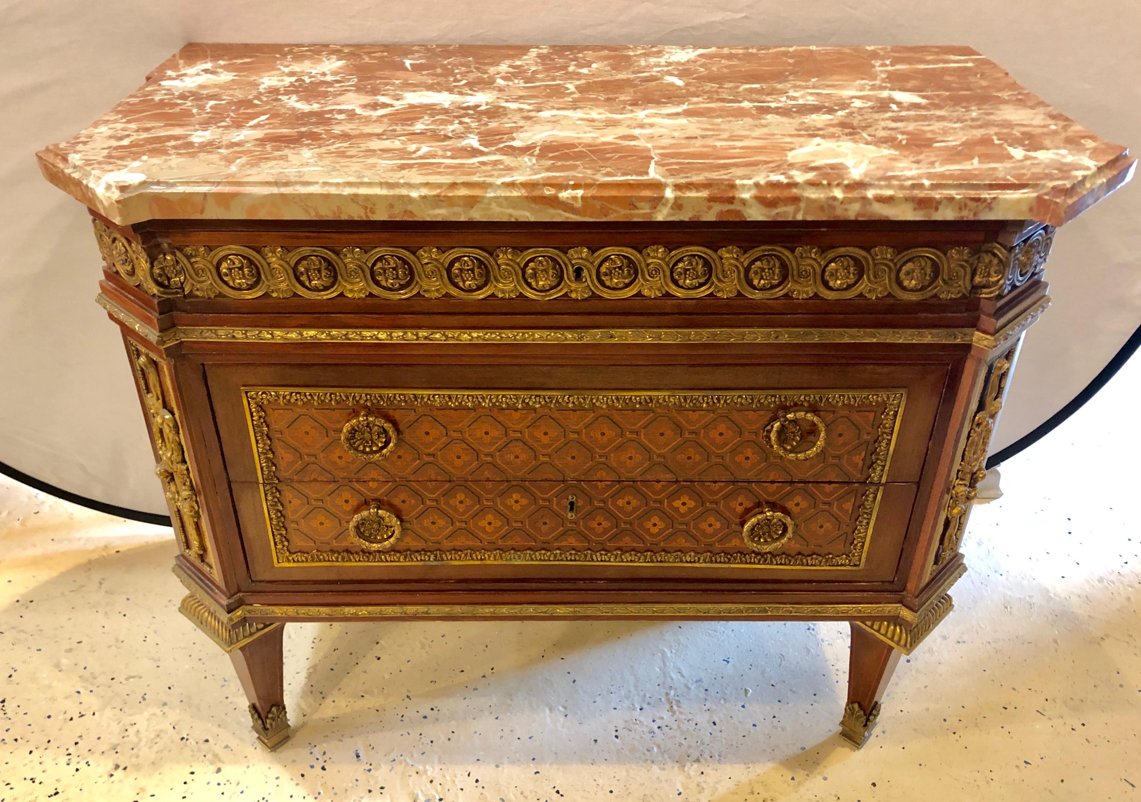 Spectacular bronze-mounted marble-top parquetry commode, chest or nightstand. Louis XVI style gilt bronze-mounted mahogany, kingwood and ebony parquetry commode. Fitted with a marble-top with canted corners above a frieze drawer and a pair of