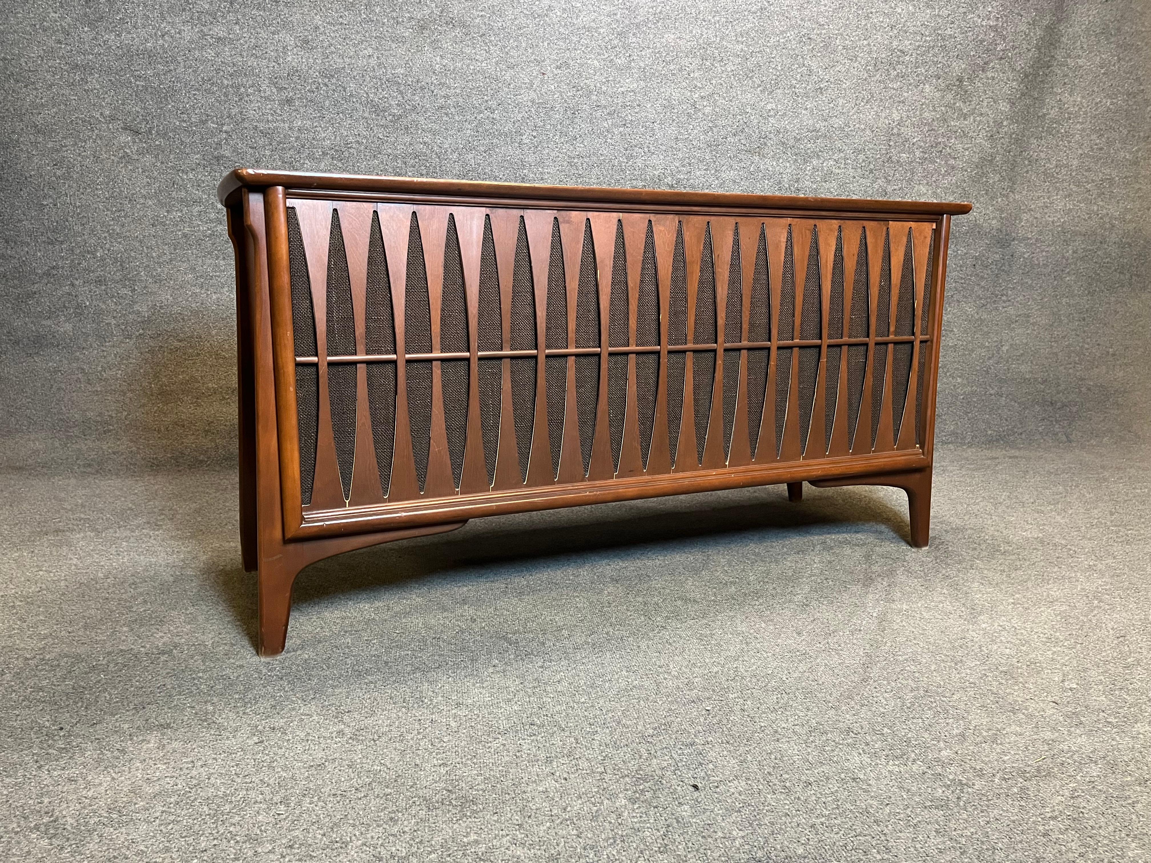 This rare RCA console stereo features one of the best looking Mid Century designs that we have seen. The entire front is lined with curved walnut slats that are bent around a horizontal dowel. The effect is reminiscent of Broyhill Brasilia designs.