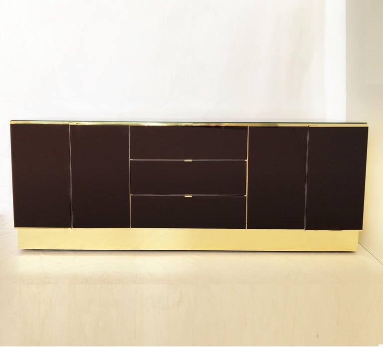 Glamorous dresser is clad in brass and painted glass by Ello Furniture. The burgundy colored glass is absolutely stunning. The dresser and chest feature a panel case, overlaid with mirrored panels, including tab pulls and terminating in a plinth