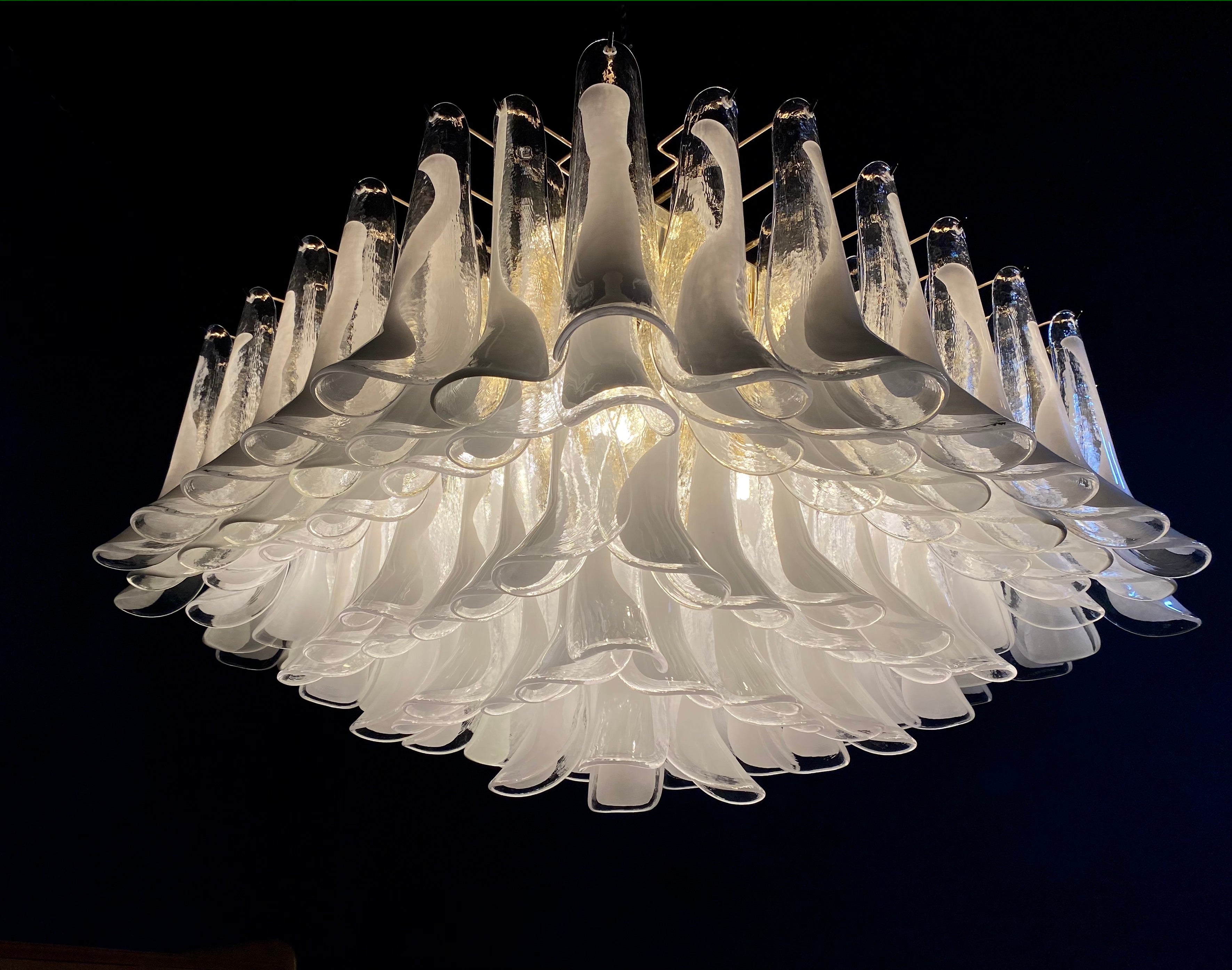 Riesiger Kronleuchter aus Murano-Glas mit weißen Blütenblättern  mit 122 mundgeblasenen Edelgläsern. 
Rahmen aus Messing mit  16 Glühbirnen E 27 (4W) dimmbar.
Wir können für US-Standards verdrahten. 
Maße: 95 cm x 95 cm.
Höhe: 50 cm.


