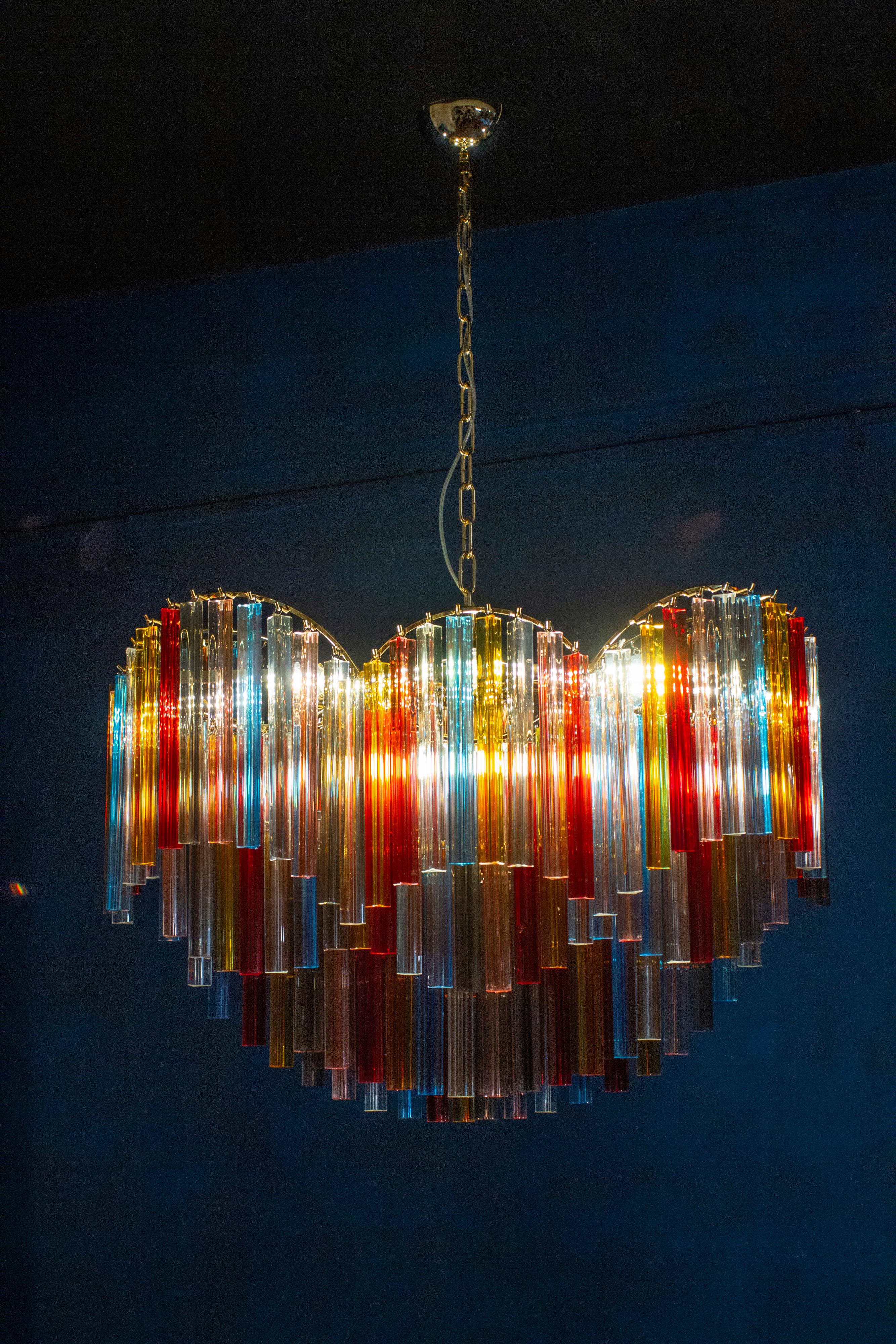 Outstanding Murano chandelier made by Murano crystal multicolored triedi prism on four levels with a gold metal frame.
The glasses are Aquamarine, transparent, blue, smoky, purple, yellow, pink and orange , creating a fabulous light