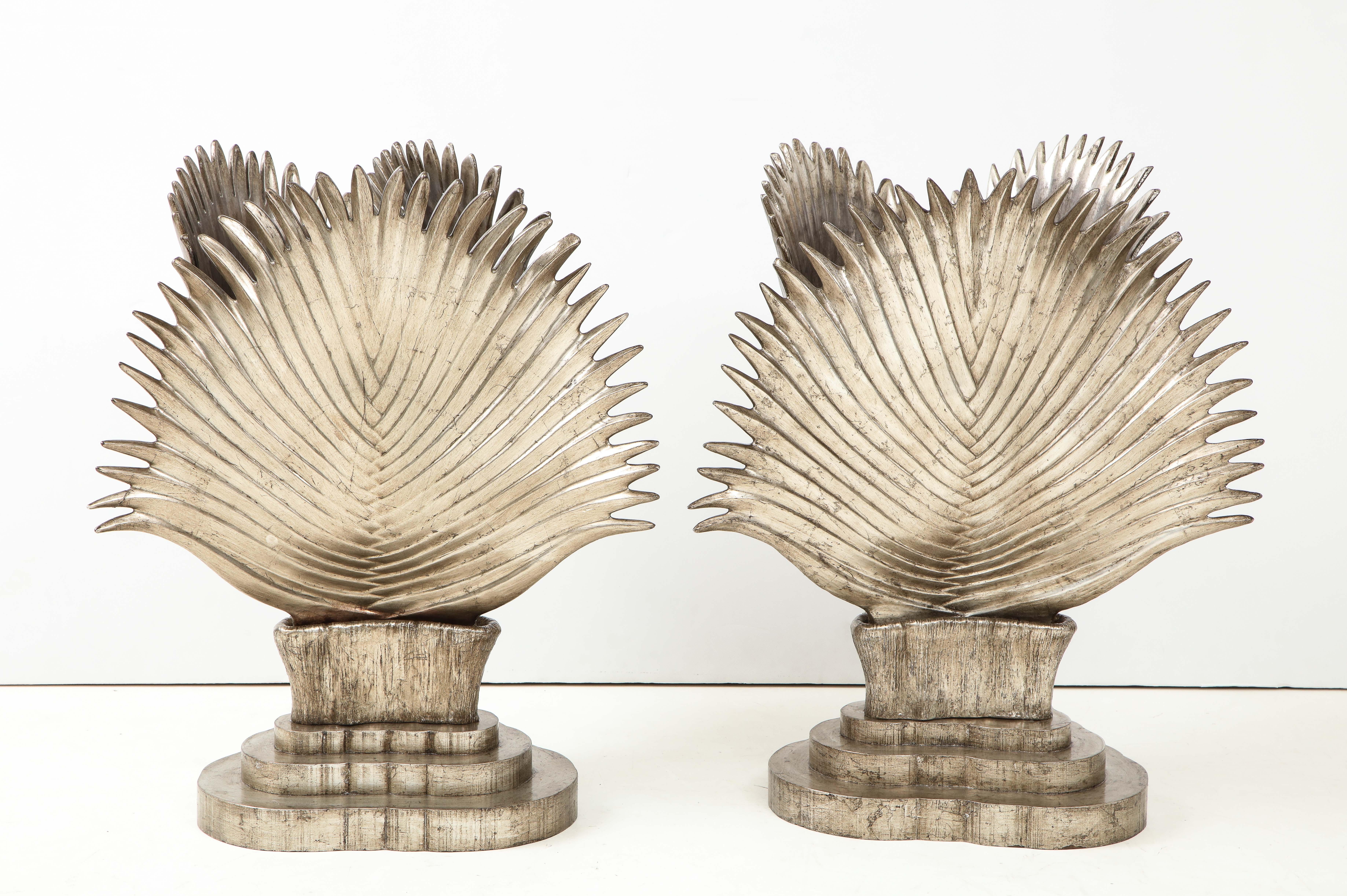 Spectacular pair of Italian ceramic Palm frond lamps.
The three handmade leaves are joined together to create a triangular shape and
they have a beautiful glazed silver leaf finish which looks like metal.
The lamp bodies sit on tiered wooden