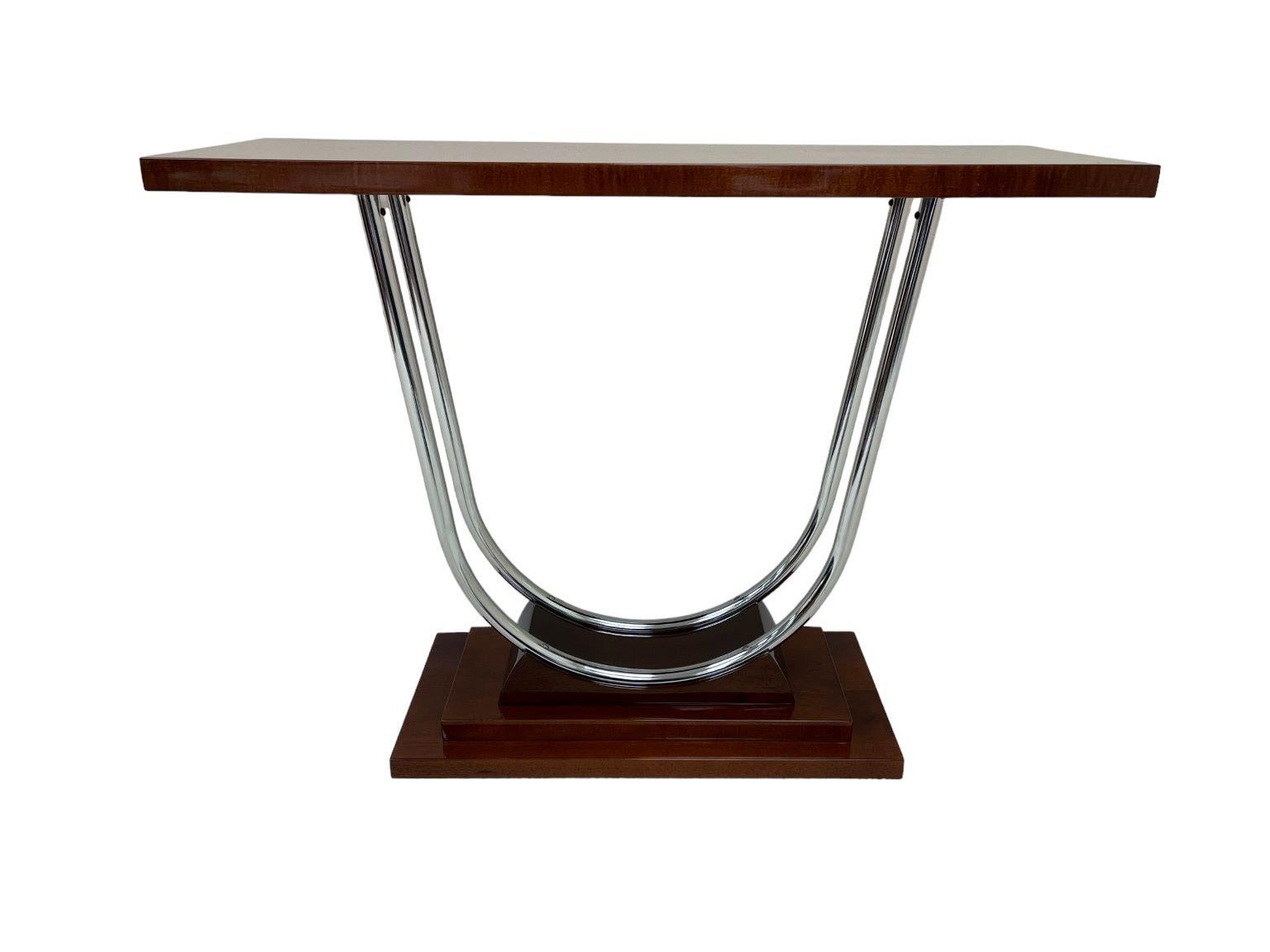 An exquisite Art Deco streamline chrome console table. Beautifully crafted and restored solid maple-stained mahogany. A simple streamline design, stout top supported by two polished chrome supports all sitting on a skyscraper base. An excellent
