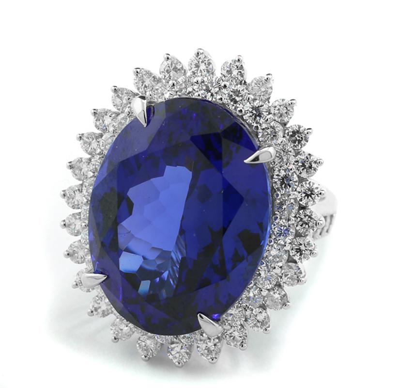 Ring with an exceptional Tanzanite of 28.28 carats, oval cut, color: deep Royal Blue, very fine colour saturation and brilliancy, eye-clean quality, set in a four-prong setting. The gemstone is accented with two rows of white brilliant-cut diamonds,