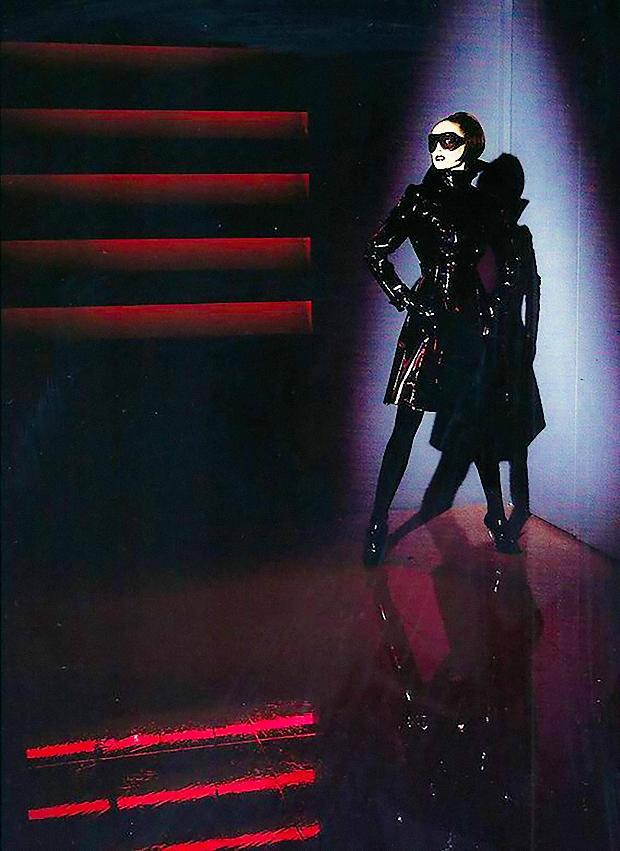 Iconic black Thierry Mugler’s Fall/Winter 1996Les Amazones Collection Bombshell vinyl trench coat. 
This stunning jacket exudes a hypnotic blend of dominance and sophistication. Its sculptural silhouette flatters the form with precision, while the