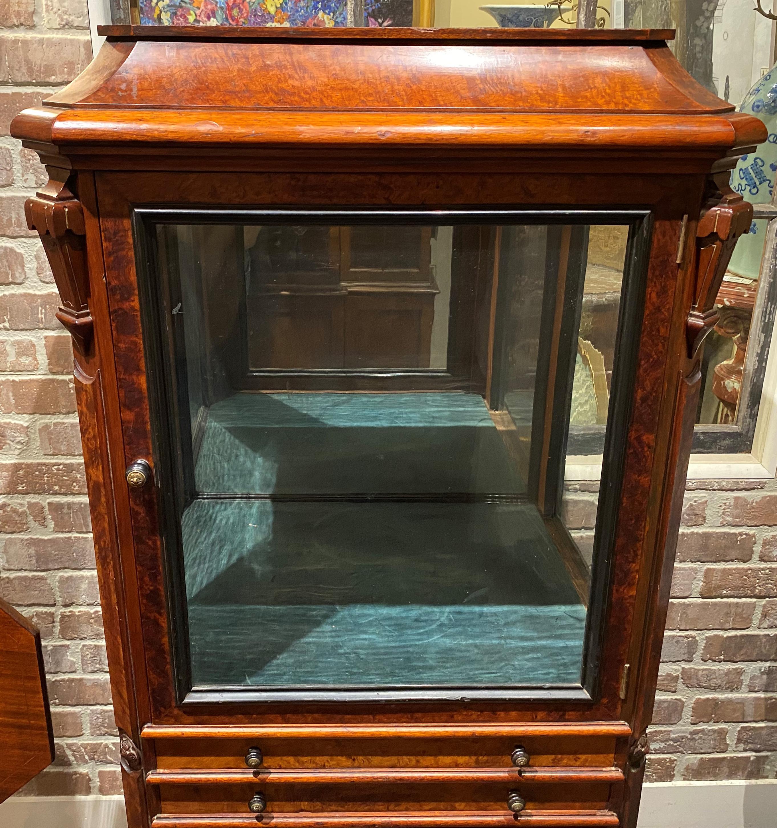 A fine Victorian Eastlake or Aesthetic collectors cabinet in walnut and burled walnut veneer, with molded rectangular top with canted corners surmounting a display compartment with single glass door and two glass sides and mirrored back, and velvet