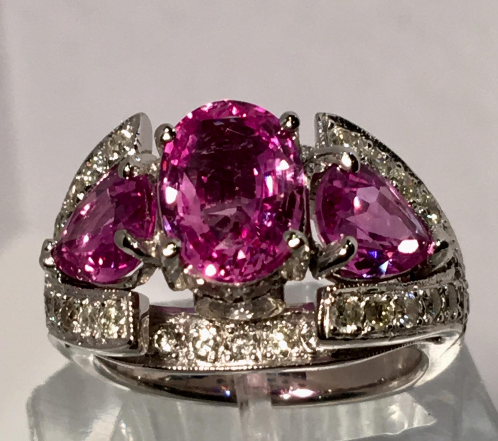 Fantastic from all angles, this custom made, substantial platinum estate three stone ring or engagement ring features a prong set oval cut pink sapphire, flanked with two prong set, pear cut pink sapphire stones, with two bezel set round brilliant