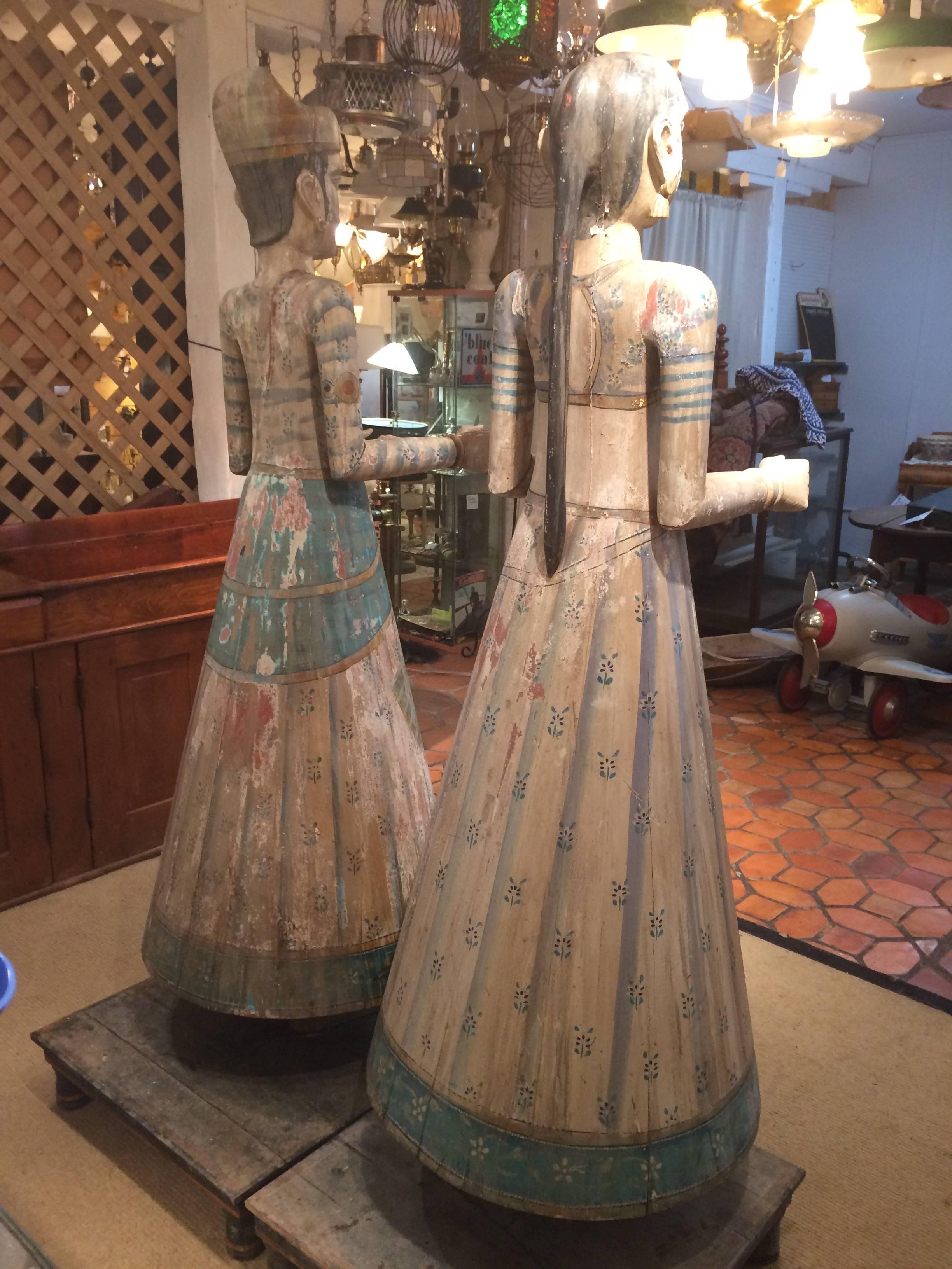 Two extremely large gorgeous vintage Rajasthani figures that may be god and goddess, all hand carved and painted in beautiful naturally distressed condition, having lovely gestural hands, a soft pastel color palette, and original wooden stands. Man