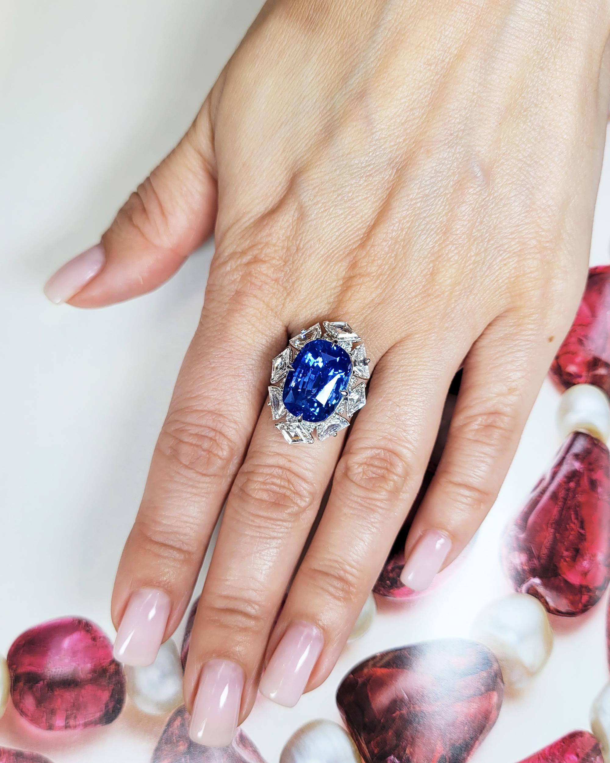 Eine fesselnde Kreation von zeitloser Eleganz. Im Mittelpunkt dieses exquisiten Rings steht ein prächtiger 13,57-karätiger Saphir im Kissenschliff aus Madagaskar, der einen tiefen und faszinierenden Blauton ausstrahlt. Der Saphir ist