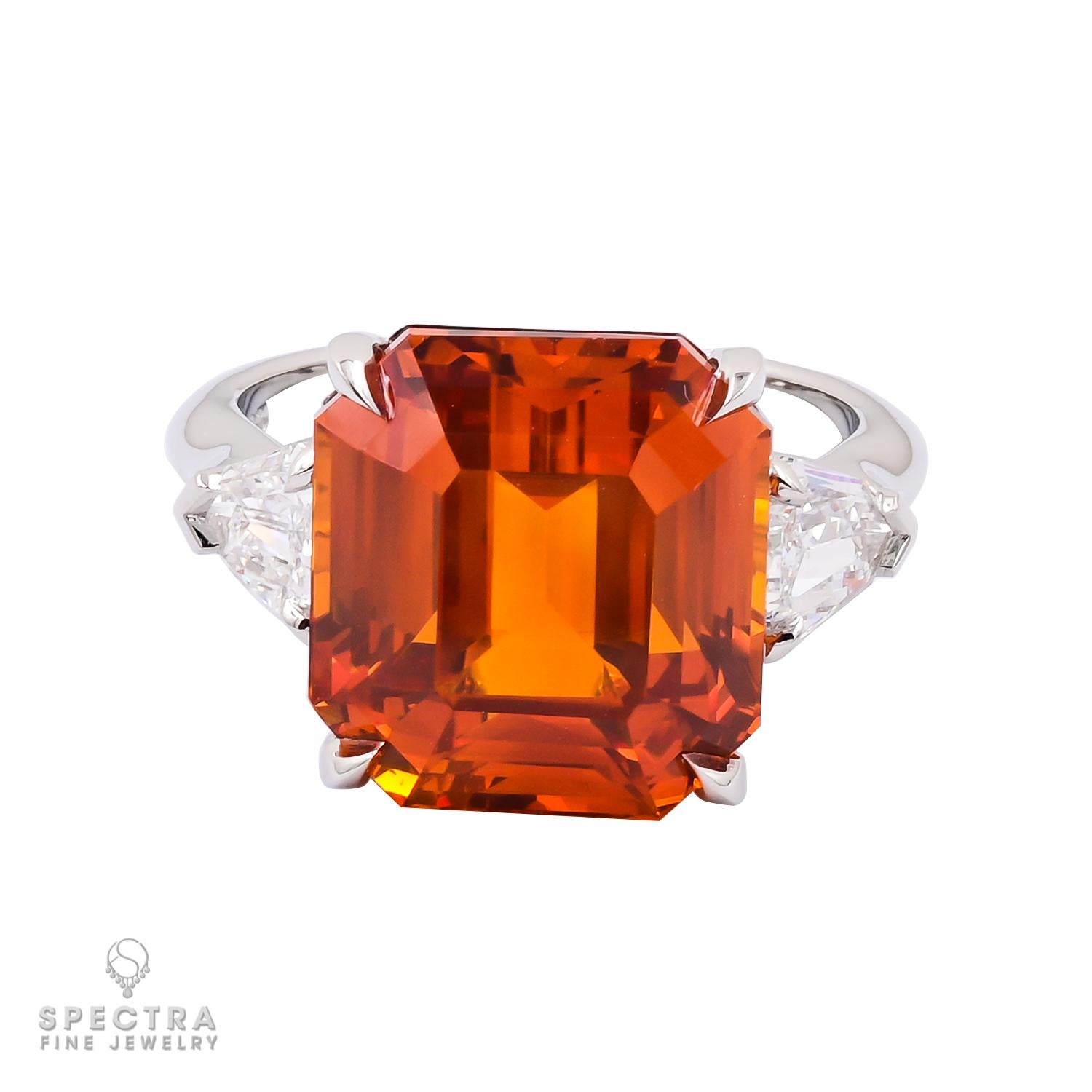 This breathtaking Cocktail Ring feature a magnificent emerald-cut orange sapphire at its center. Weighing an impressive 13.06 carats, this gemstone commands attention with its vivid hue and remarkable clarity.

Certified by the prestigious